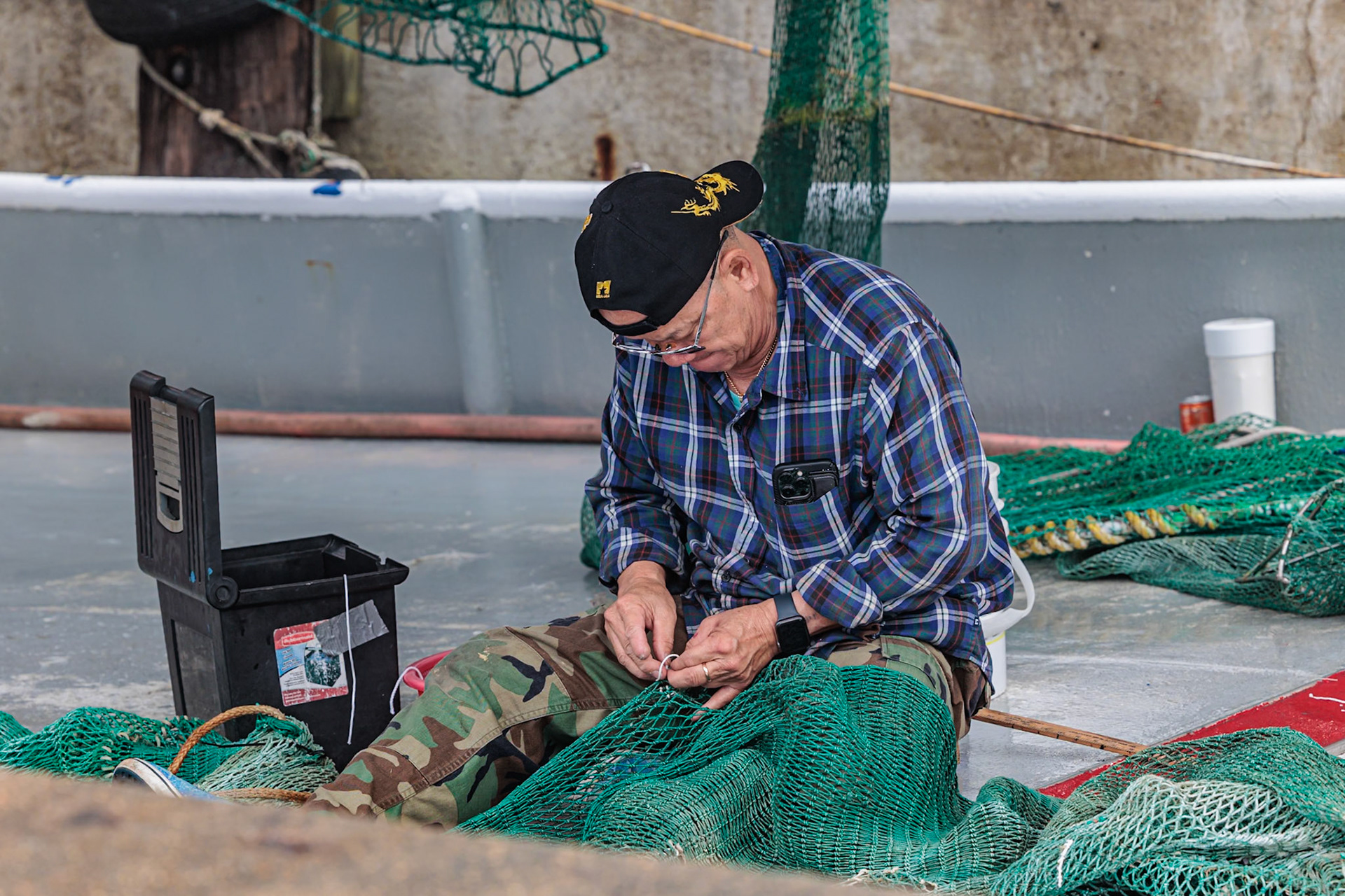 211231_123 Commercial fisherman on his shrimp boat repairing his nets at the Biloxi Small Craft Harbor in Biloxi, Mississippi