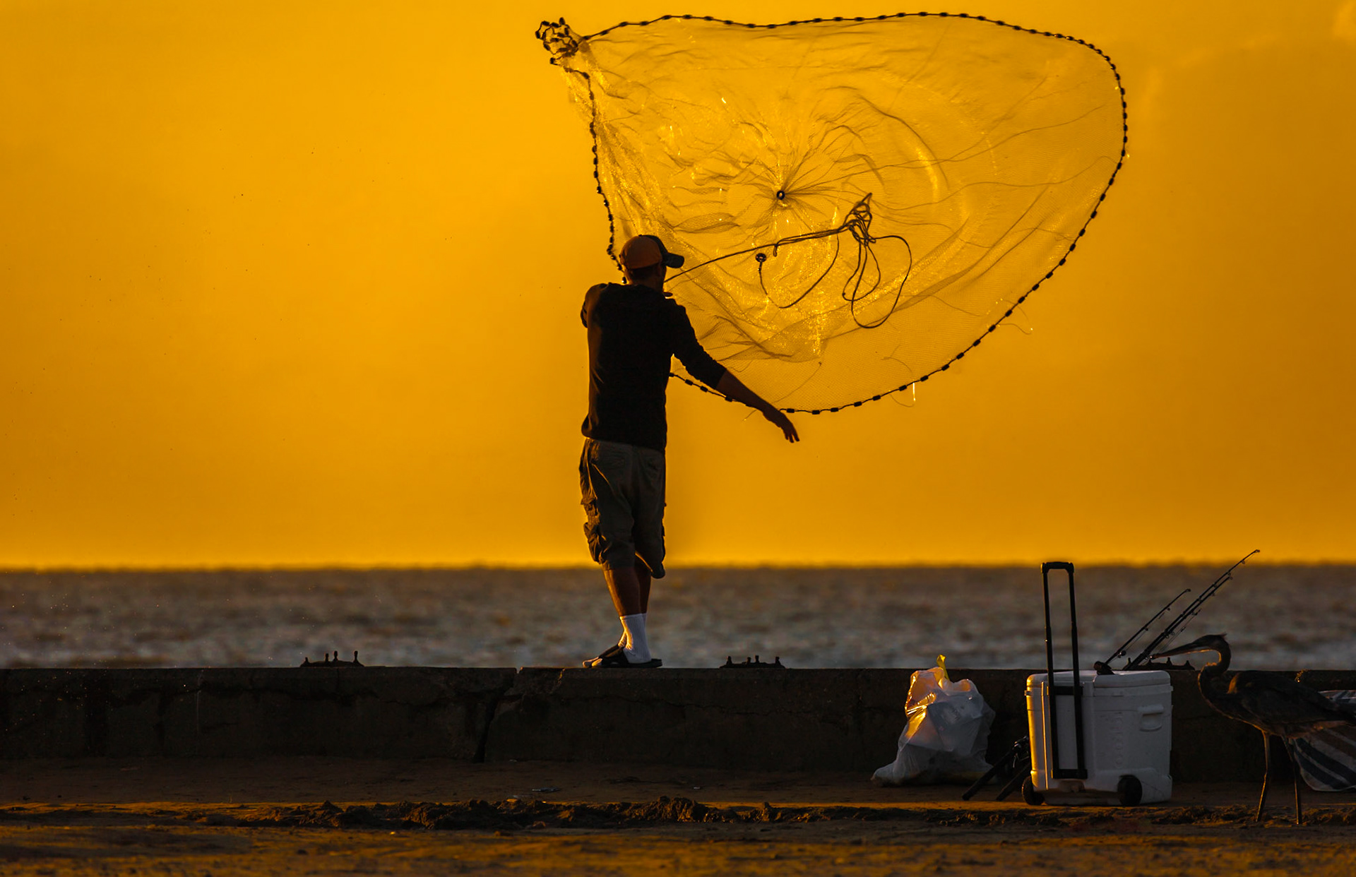 140924_044. Man throwing cast net into the Gulf of Mexico at the old Broadwater Marina in Biloxi, Mississippi
