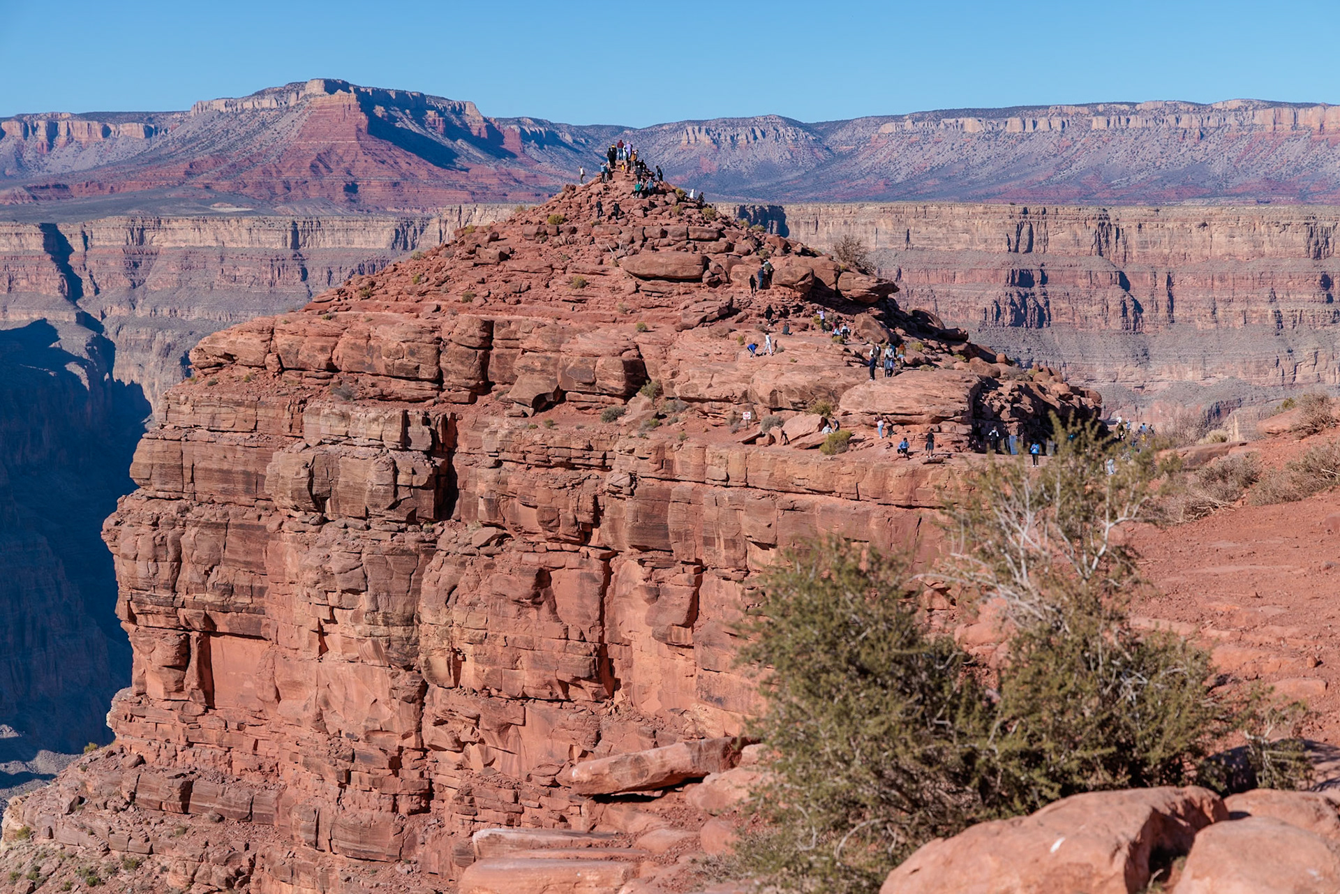 230405_261 Visitors climb on rock formation rising above the canyon at Guano Point in Grand Canyon West near Peach Springs, Arizona