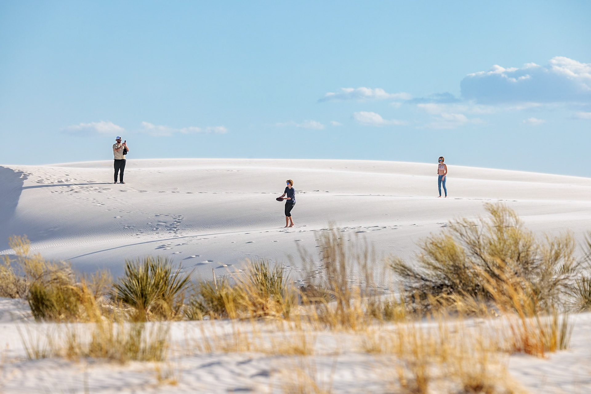 230323_113 Man and teen children playing frisbee on the gypsum dunes at White Sands National Park near Alamogordo, New Mexico