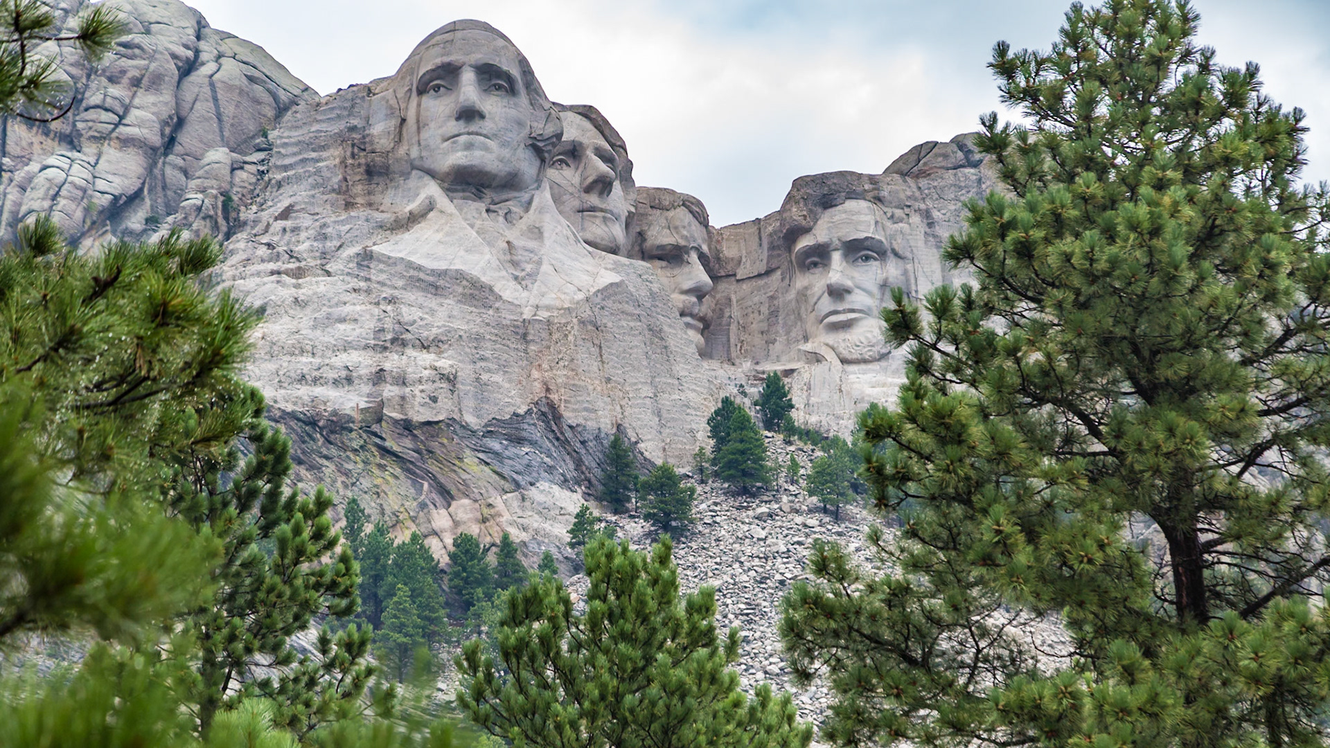 180814_035 Carved granite busts of George Washington, Thomas Jefferson, Theodore "Teddy" Roosevelt and Abraham Lincoln framed by pine trees at Mount Rushmore National Monument near Keystone, South Dakota