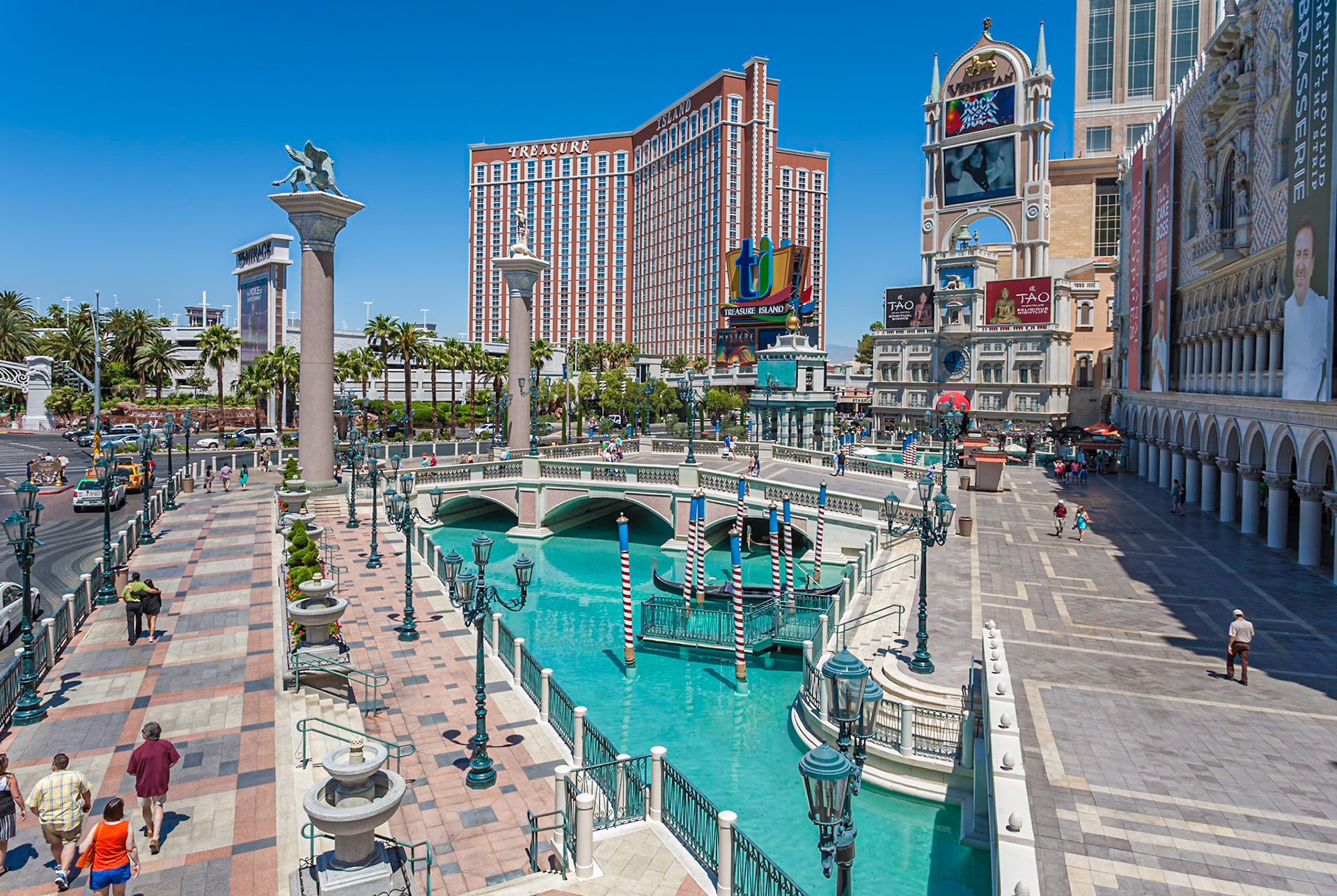 140502_659 Treasure Island hotel and casino rises up beyond the pools of the Venetian resort on the Las Vegas Strip in Paradise, Nevada