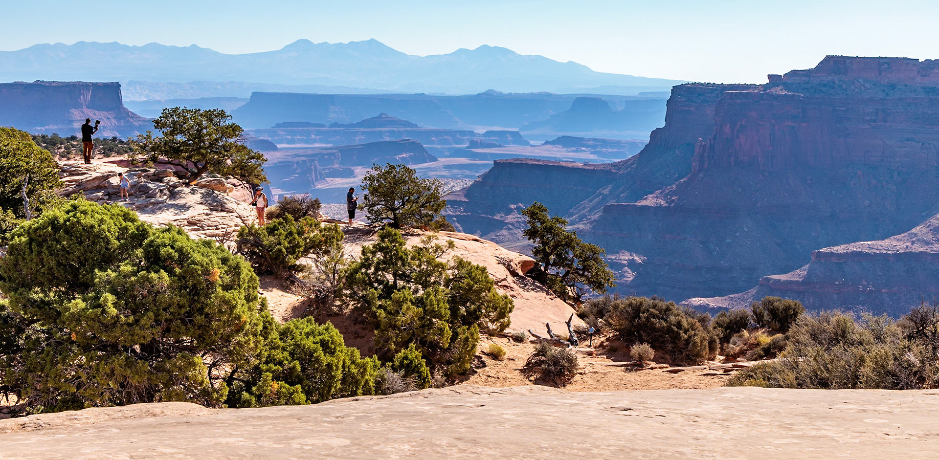 240928_003 Visitors climbing on the rocks and photographing the valley in the Island in the Sky area of Canyonlands National Park, Utah, USA