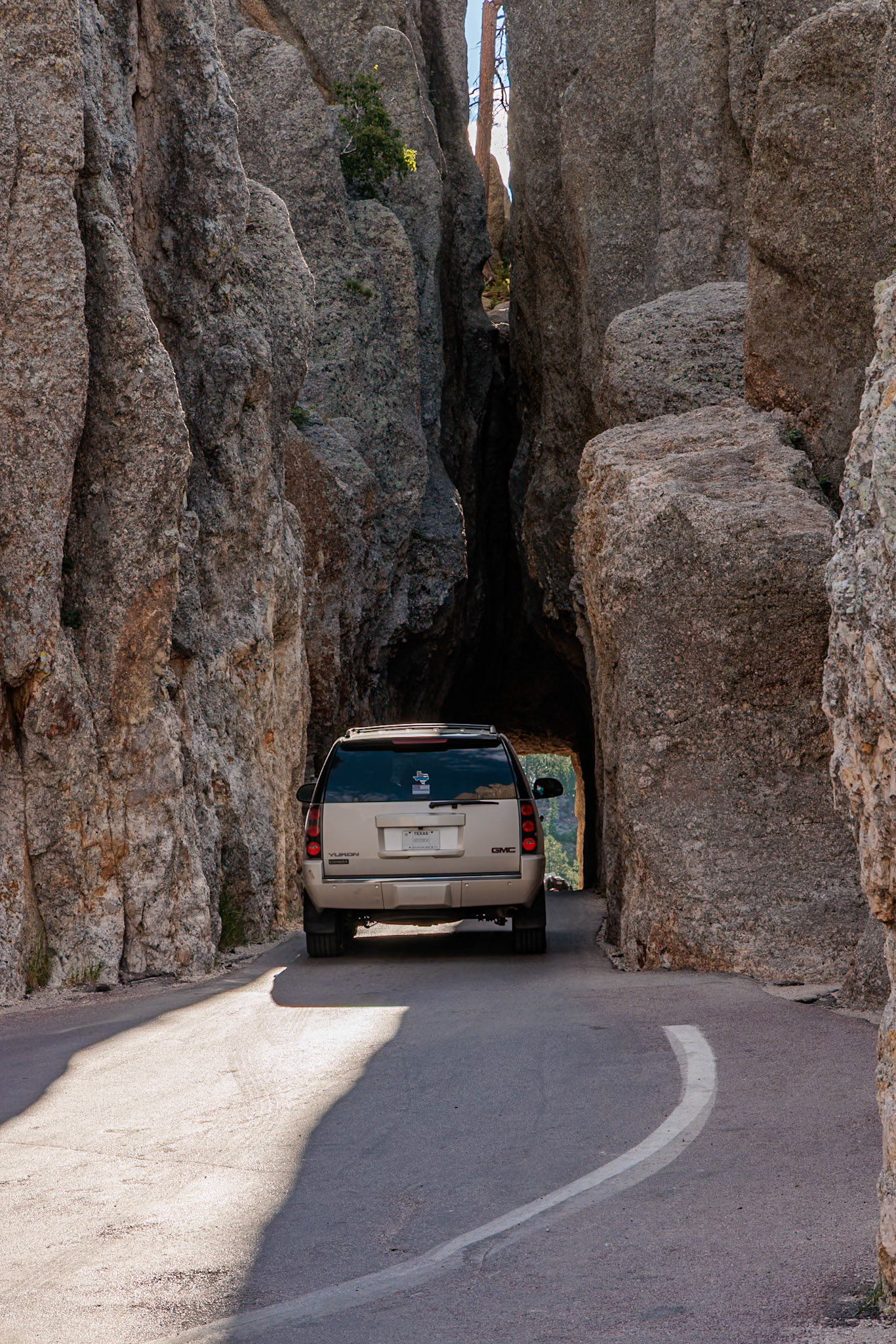 240821_065 Large SUV driving through the Needles Eye tunnel in Custer State Park, South Dakota, USA