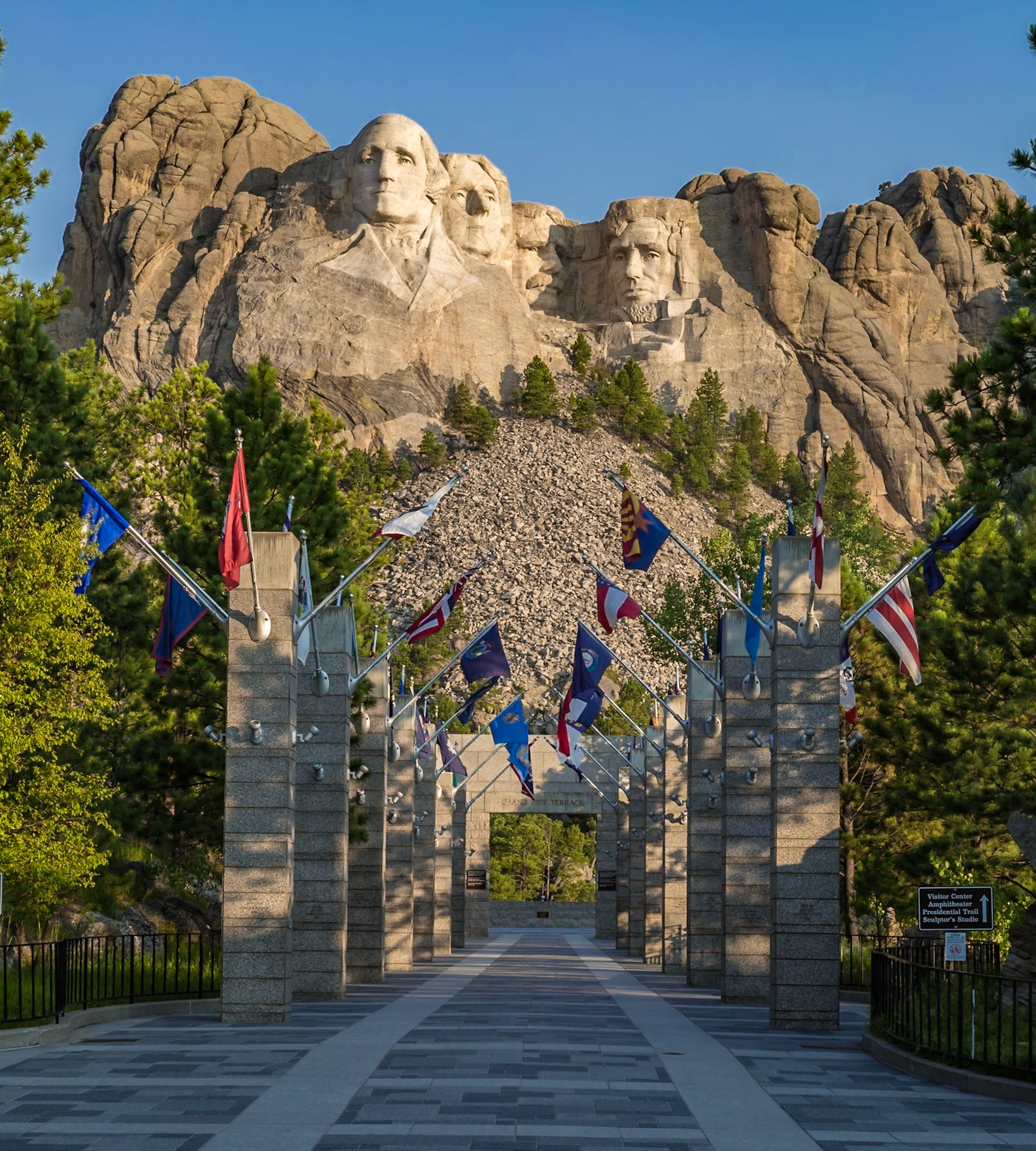 180816_005 Carved granite busts of George Washington, Thomas Jefferson, Theodore "Teddy" Roosevelt and Abraham Lincoln above the Avenue of Flags at the entrance to Mount Rushmore National Monument near Keystone, South Dakota