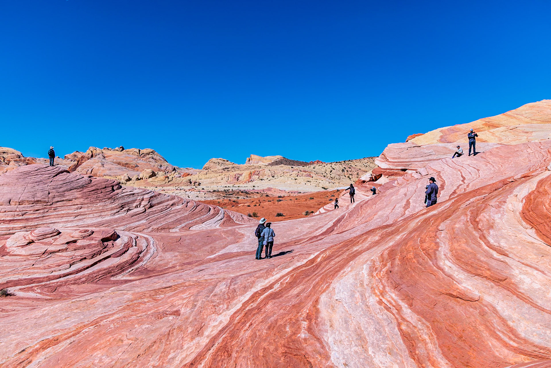 230330_149 Hikers on a layered sandstone rock formation in the Fire Wave area of Valley of Fire State Park near Overton, Nevada