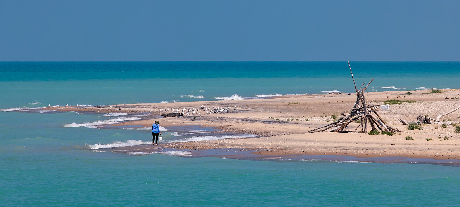 250813_080 Woman collecting rocks along the eastern shoreline of Lake Michigan near Frankfort, Michigan, USA