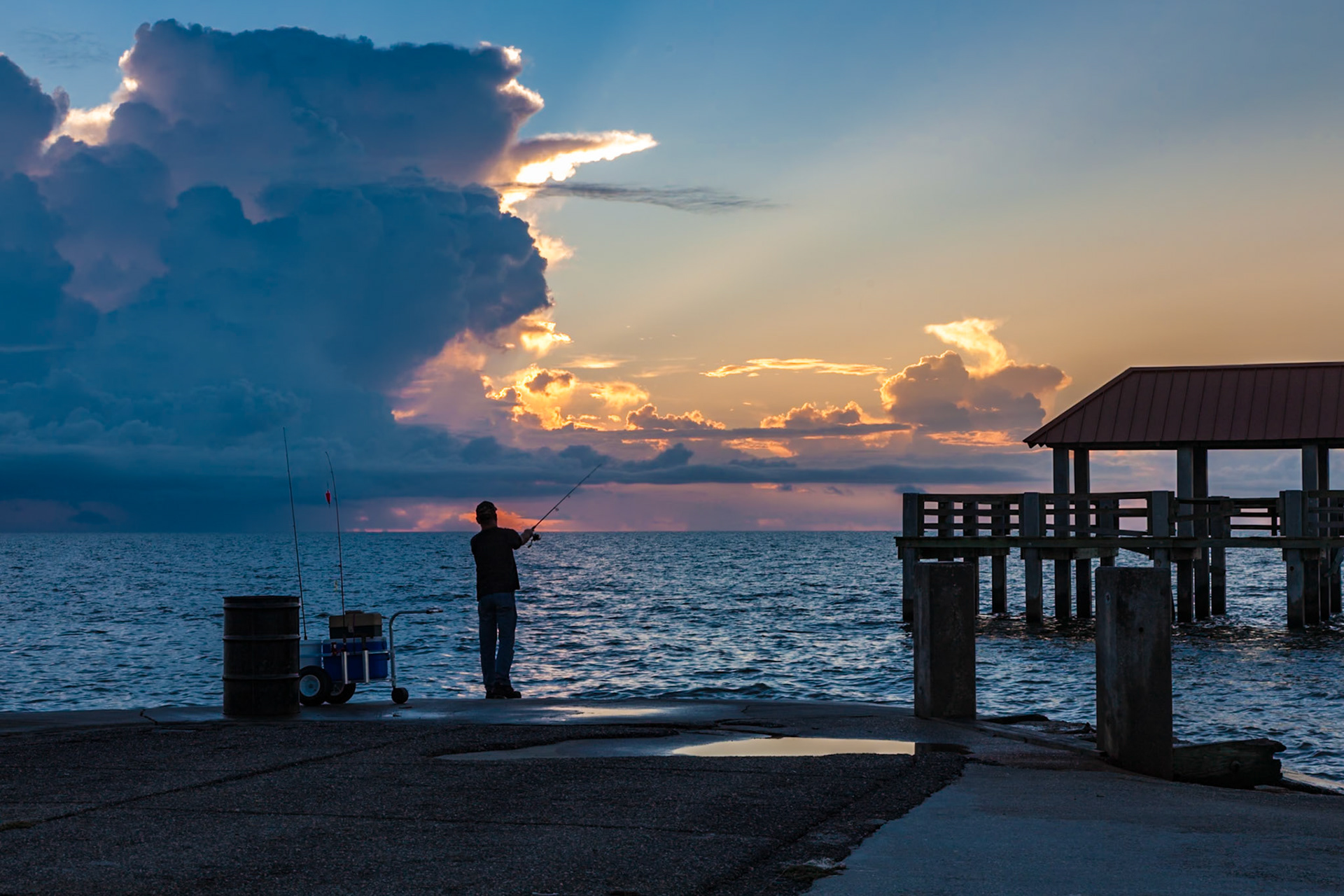 141002_053 Storm brewing offshore while a man is fishing at the Gulfport harbor in Gulfport, Mississippi