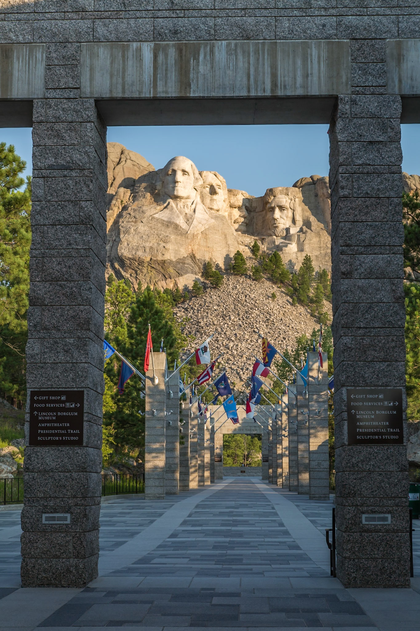 180816_004 Carved granite busts of George Washington, Thomas Jefferson, Theodore "Teddy" Roosevelt and Abraham Lincoln above the Avenue of Flags at the entrance to Mount Rushmore National Monument near Keystone, South Dakota