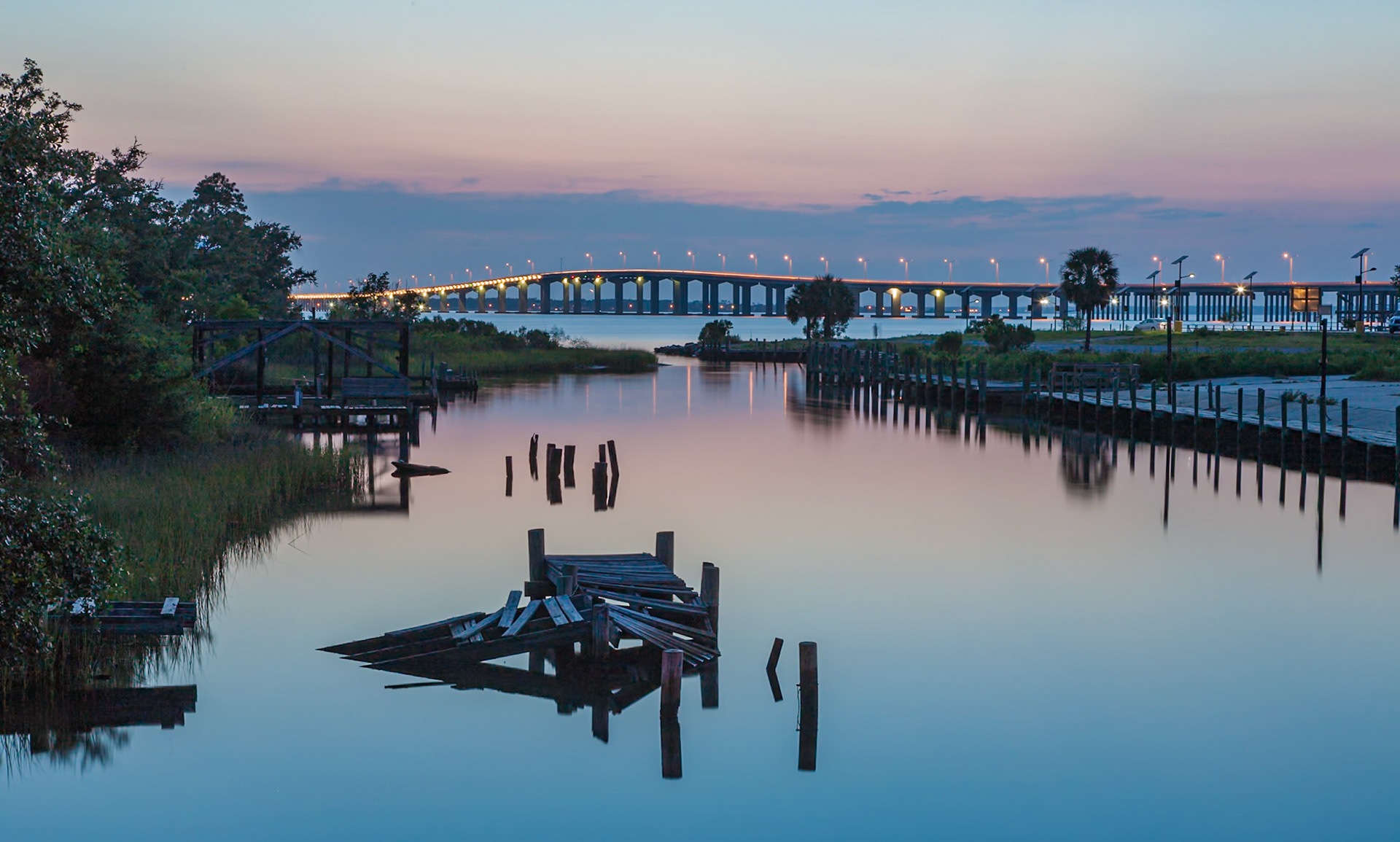 140618_023 St. Louis Bay Bridge behind the remains of an old wooden dock in a canal at Henderson Point in Pass Christian, Mississippi at sunset