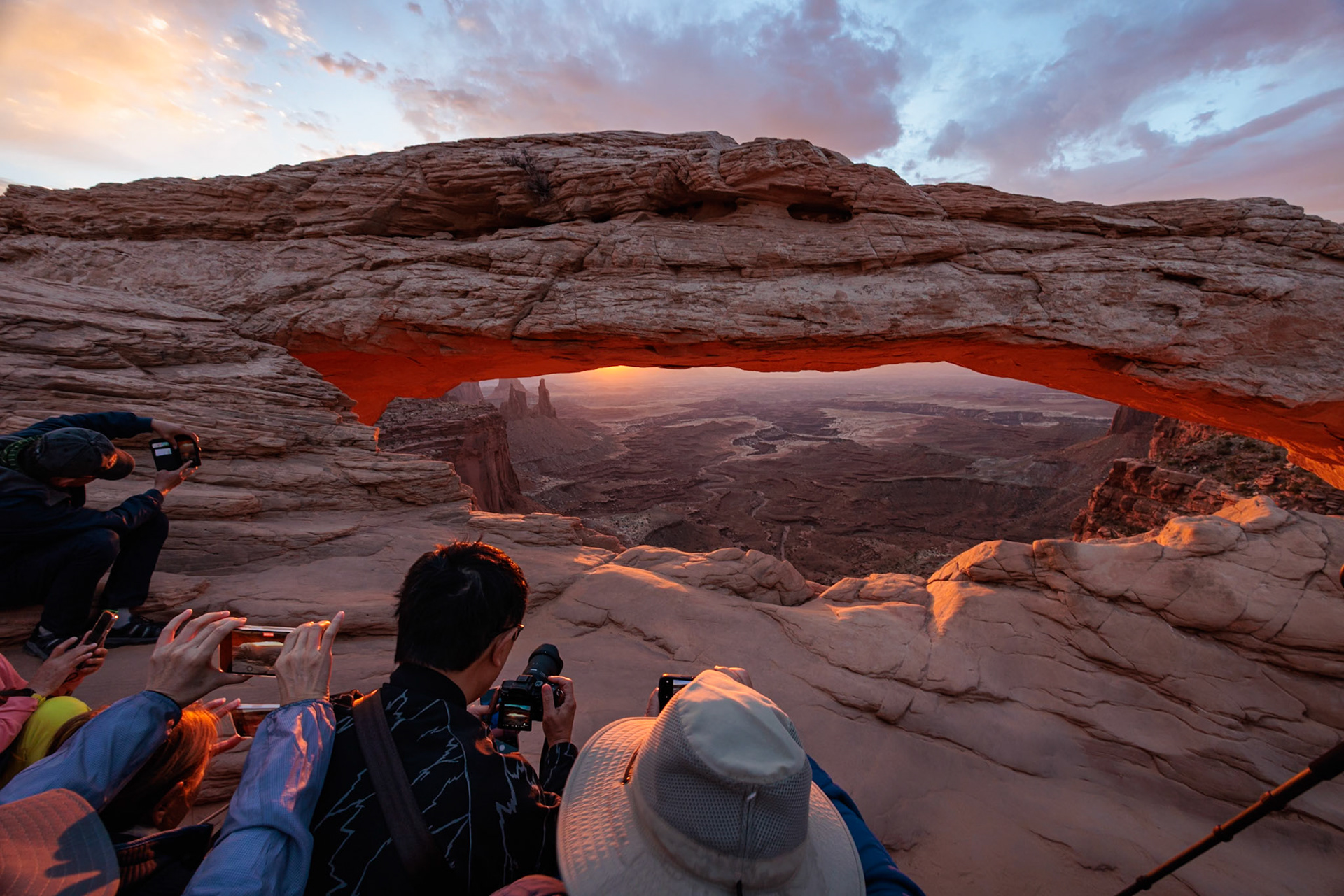 240929_004 Photographers crowd together in an attempt to photograph the Mesa Arch during sunrise in the  Island in the Sky area of Canyonlands National Park, Utah, USA