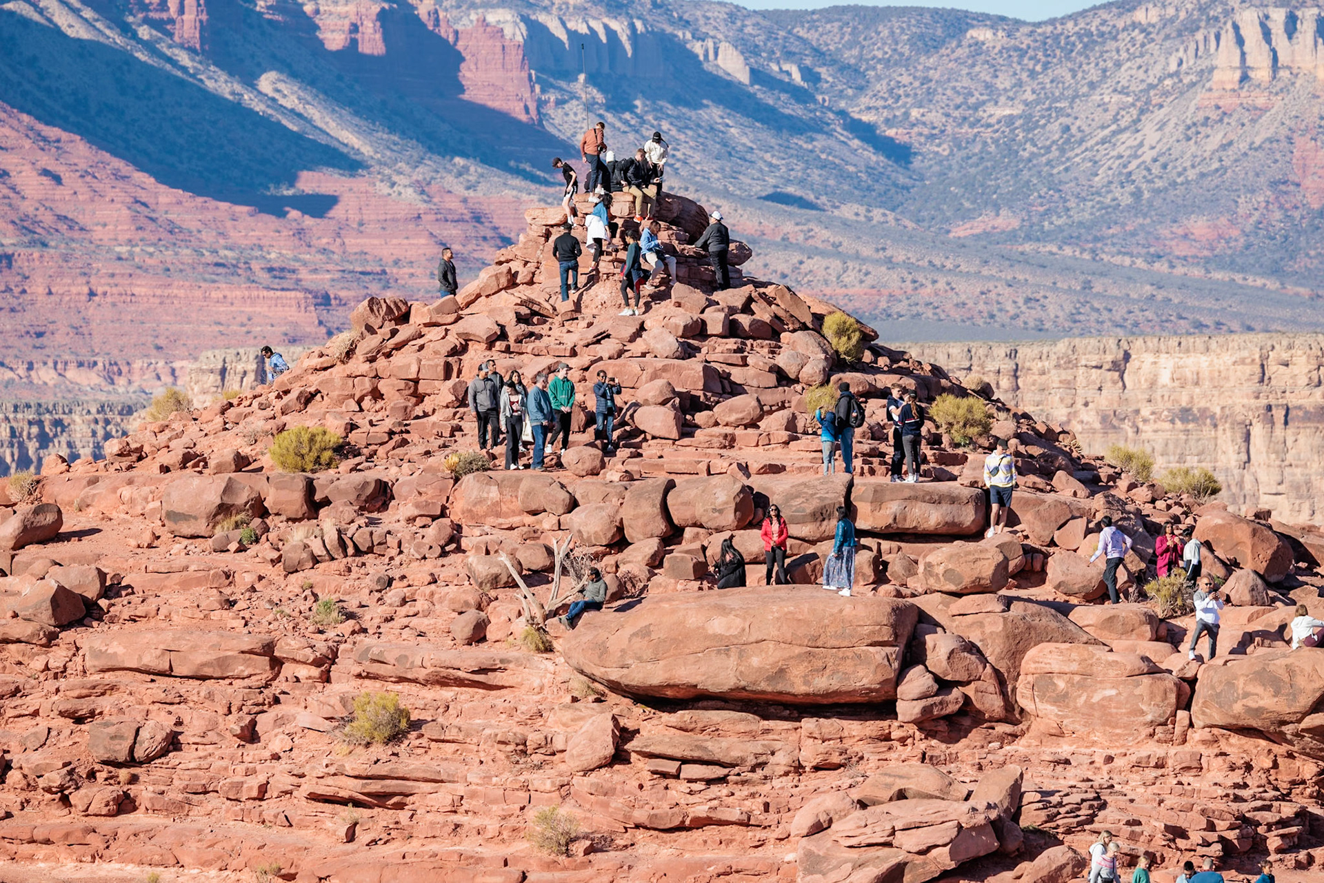 230405_274 Visitors climb on rock formation rising above the canyon at Guano Point in Grand Canyon West near Peach Springs, Arizona