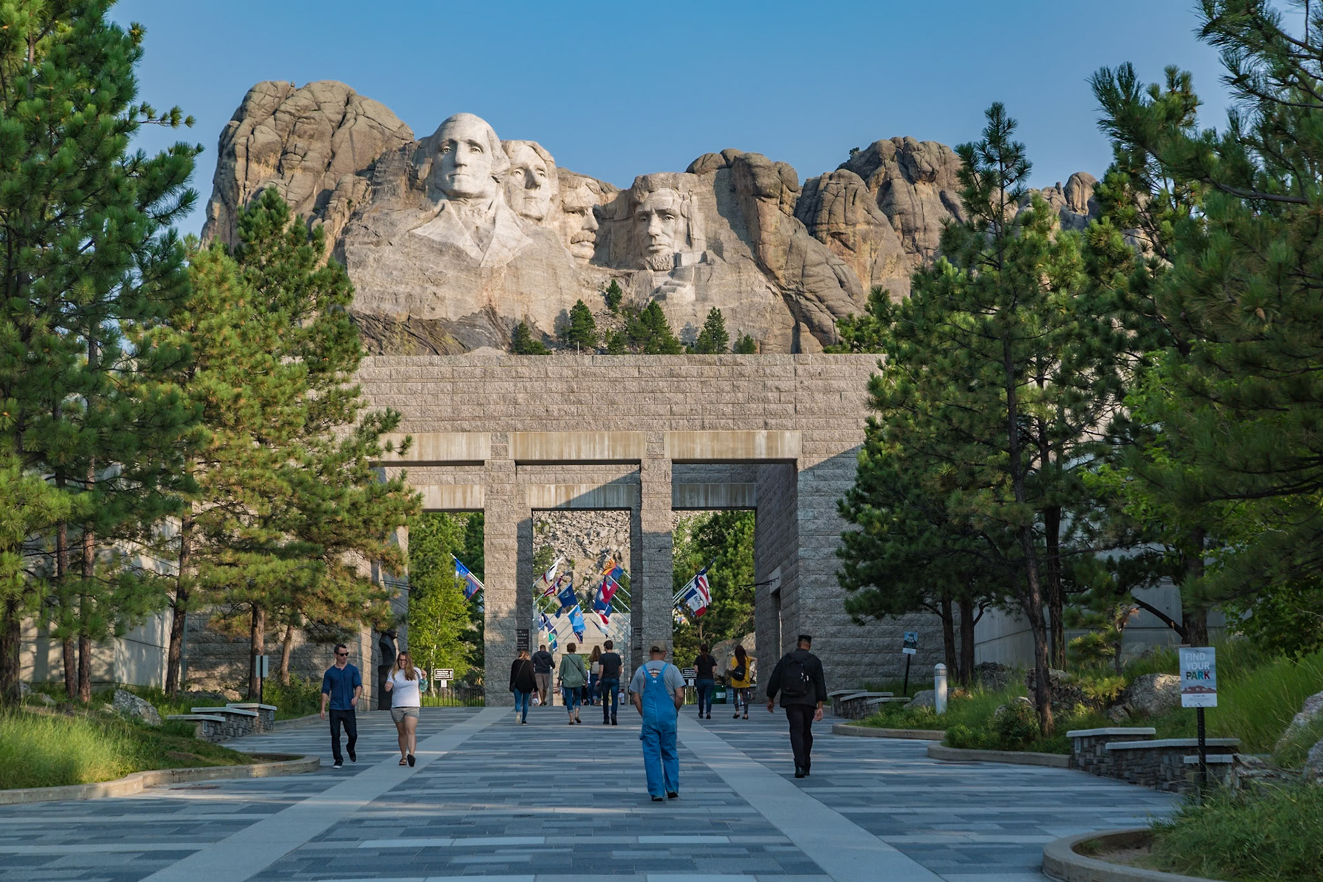 180816_106 Carved granite busts of George Washington, Thomas Jefferson, Theodore "Teddy" Roosevelt and Abraham Lincoln above the Avenue of Flags at the entrance to Mount Rushmore National Monument near Keystone, South Dakota