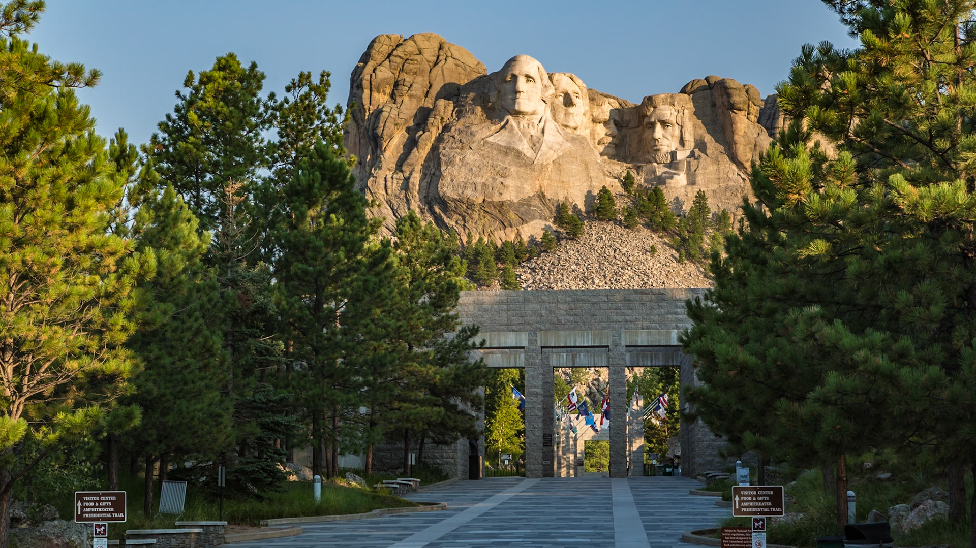 180816_001 Carved granite busts of George Washington, Thomas Jefferson, Theodore "Teddy" Roosevelt and Abraham Lincoln above the Avenue of Flags at the entrance to Mount Rushmore National Monument near Keystone, South Dakota