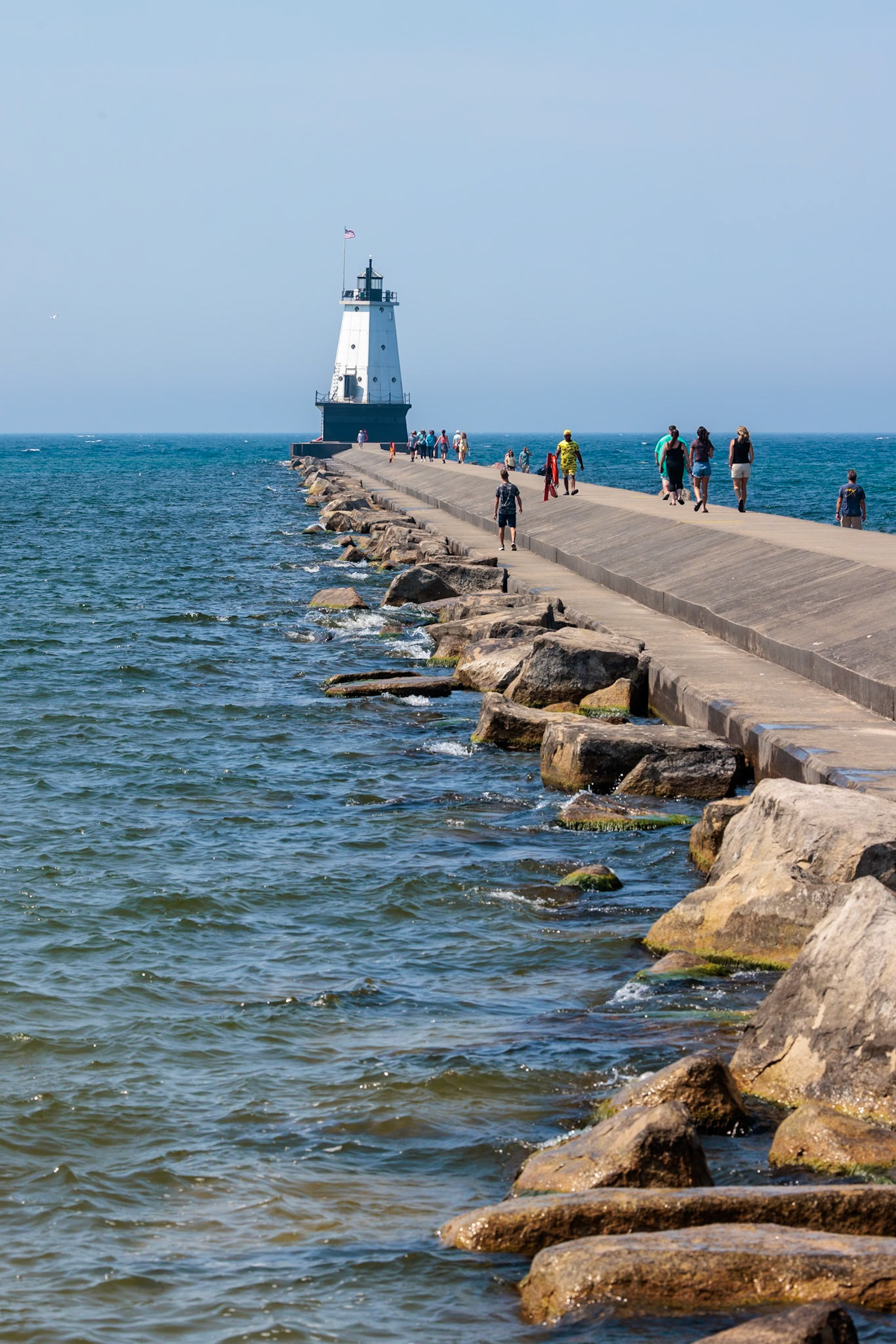 250808_048 Tourists walk along the breakwater to the Ludington North Pierhead Lighthouse in Ludington, Michigan, USA