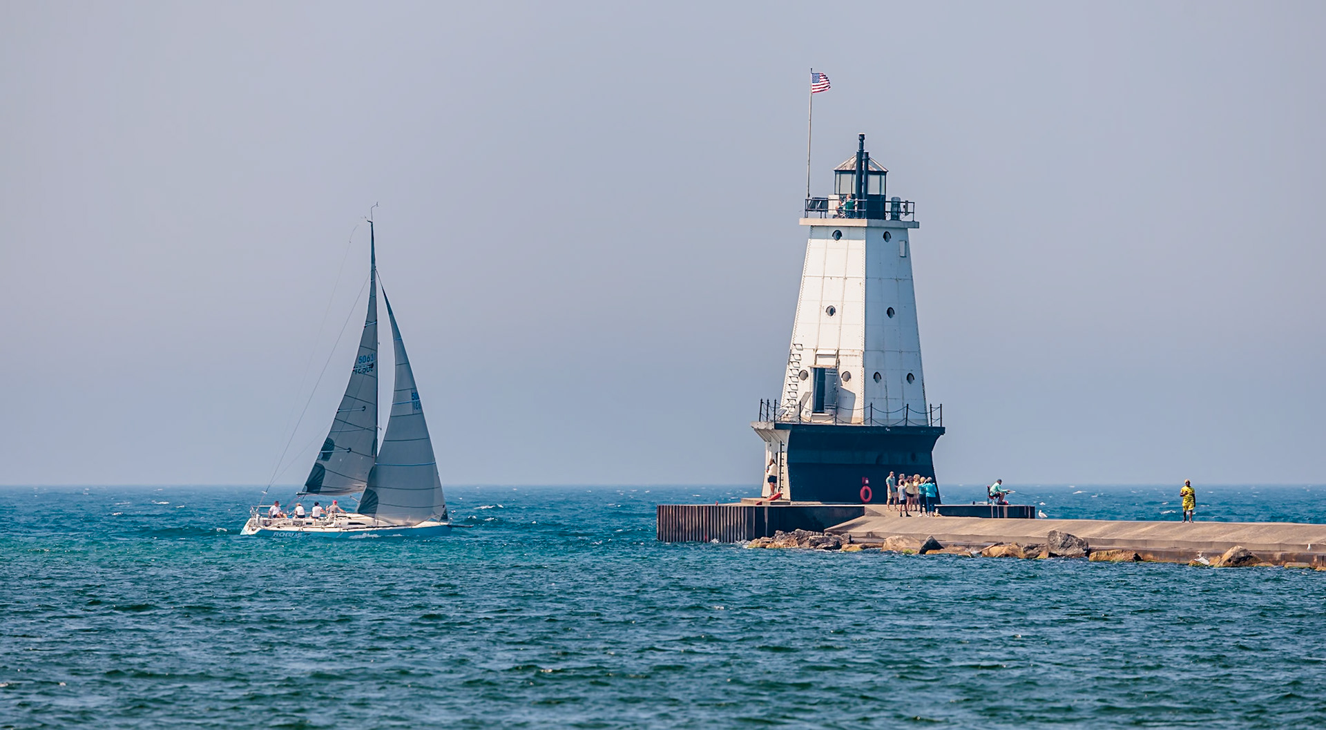 250808_028 Sailboat passing the Ludington North Pierhead Lighthouse in Ludington, Michigan, USA