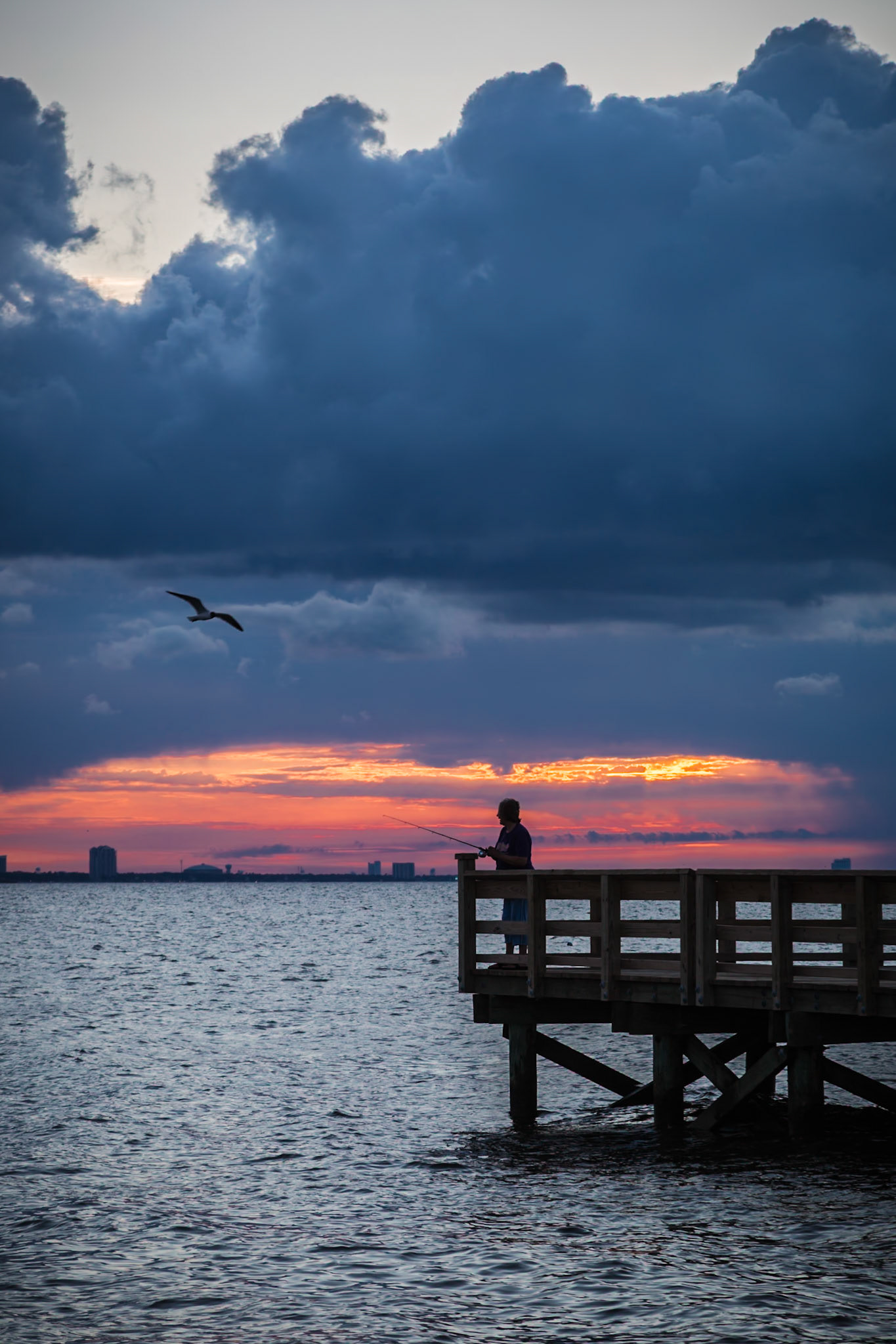 160425_255 Storm brewing offshore while a man is fishing at the Gulfport harbor in Gulfport, Mississippi