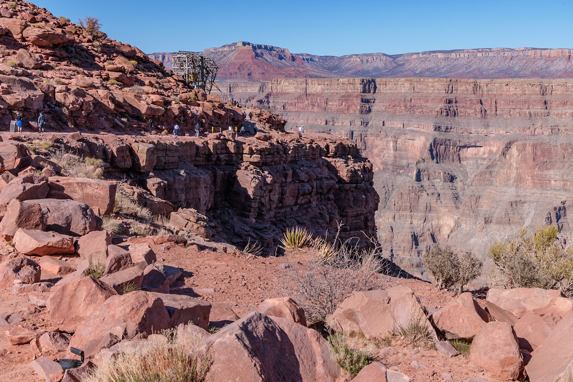 230405_230 Visitors walk along the canyon rim to the location of the old mining cable structure at Guano Point in Grand Canyon West near Peach Springs, Arizona