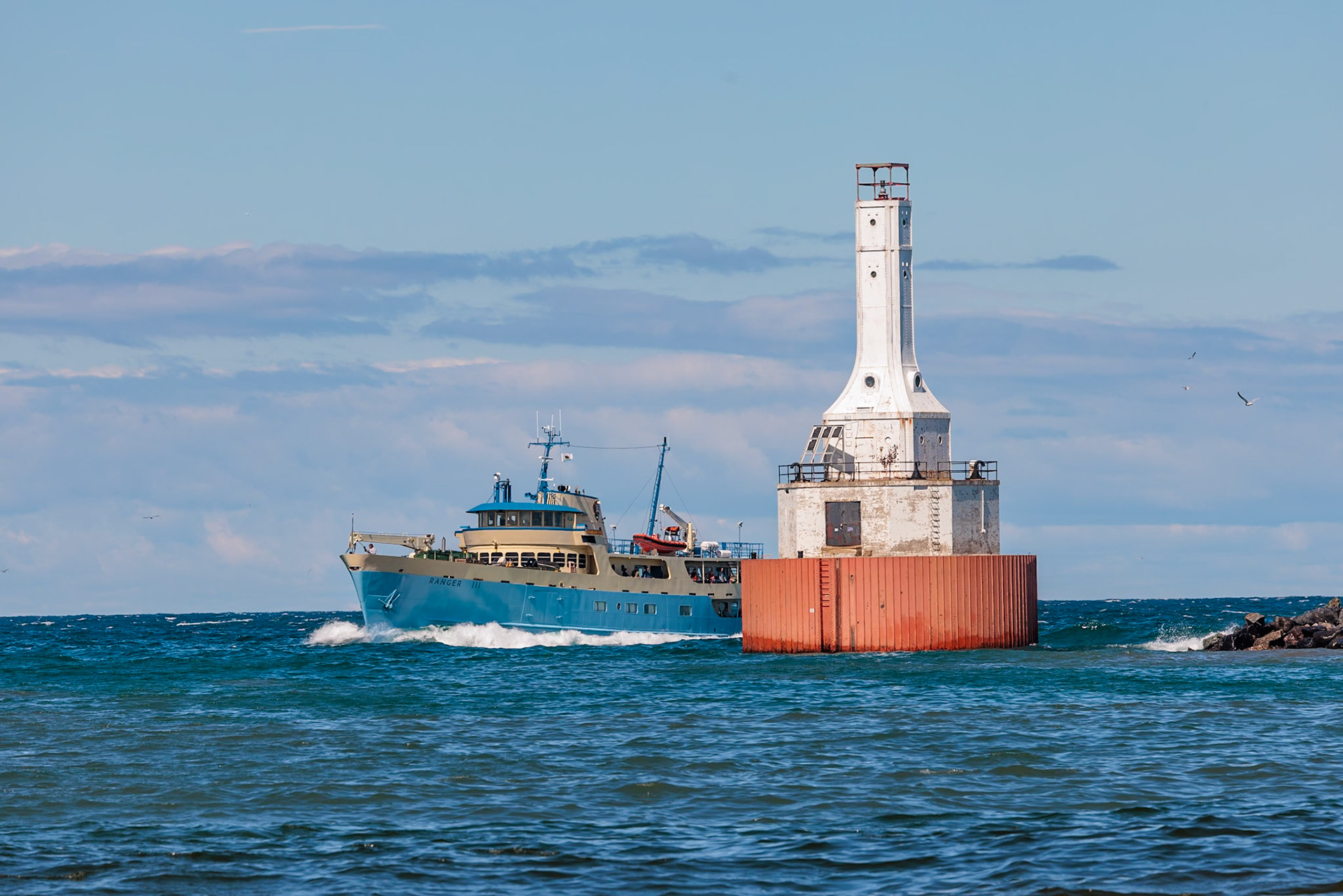 250823_023 Ranger III passenger ferry carrying tourists to and from Isle Royale National Park passes the Keweenaw Waterway Upper Entrance Light at the north end of the Portage River in McLain State Park, Michigan, USA