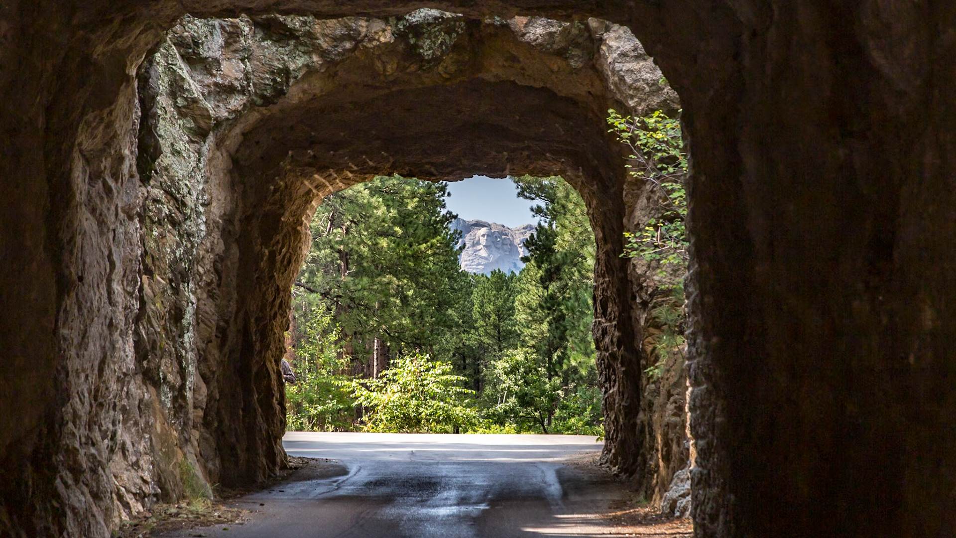 180814_105 Carved granite busts of George Washington, Thomas Jefferson, Theodore "Teddy" Roosevelt and Abraham Lincoln at Mount Rushmore National Memorial can be seen through a tunnel near Keystone, South Dakota