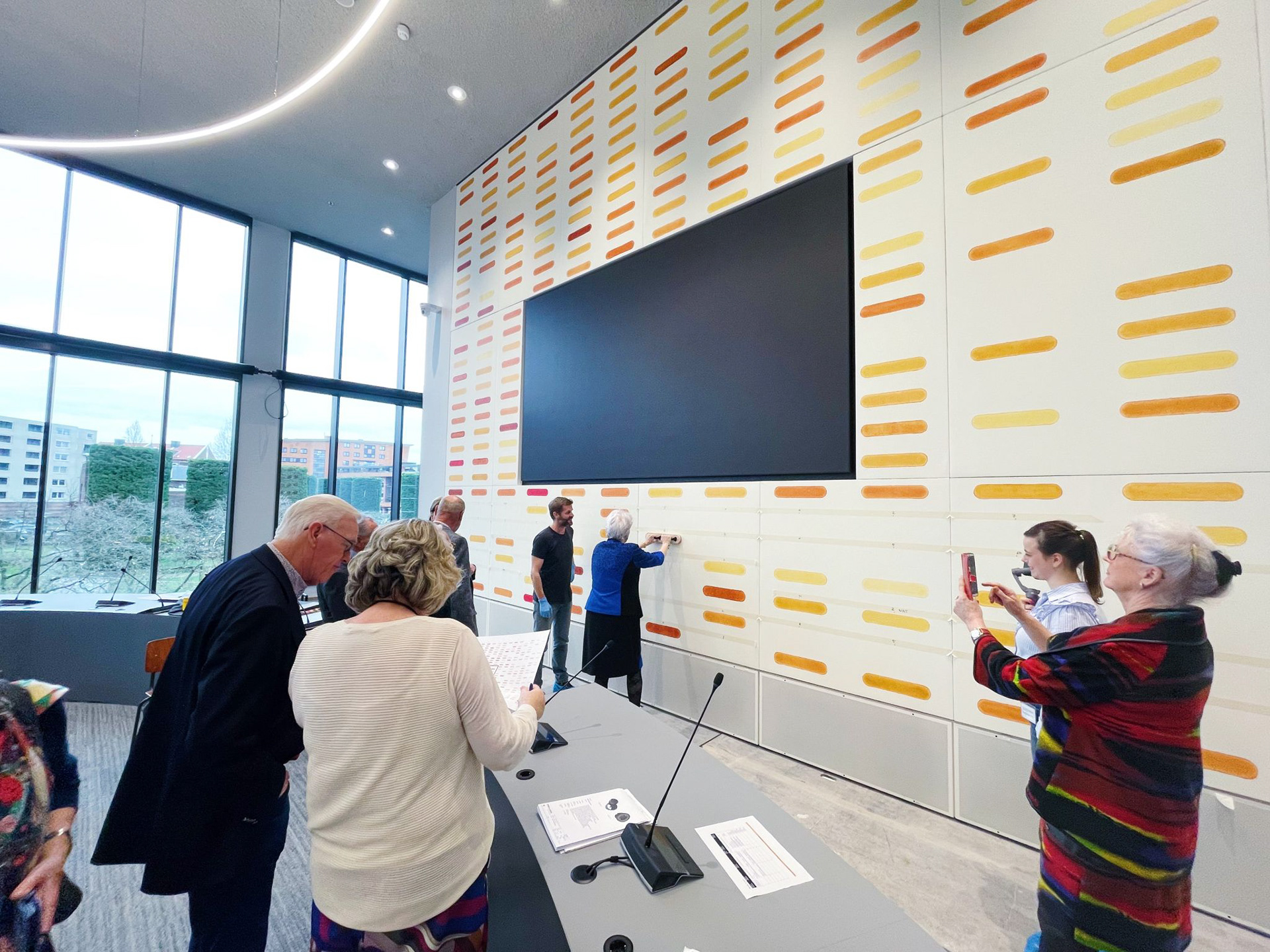 Nederlands kunstenaar Maurice van Venrooij begeleidt ereburgers tijdens de burgerparticipatie bij het werk aan zijn muurschilderingen in de raadzaal van het Huis voor de Stad in Helmond.