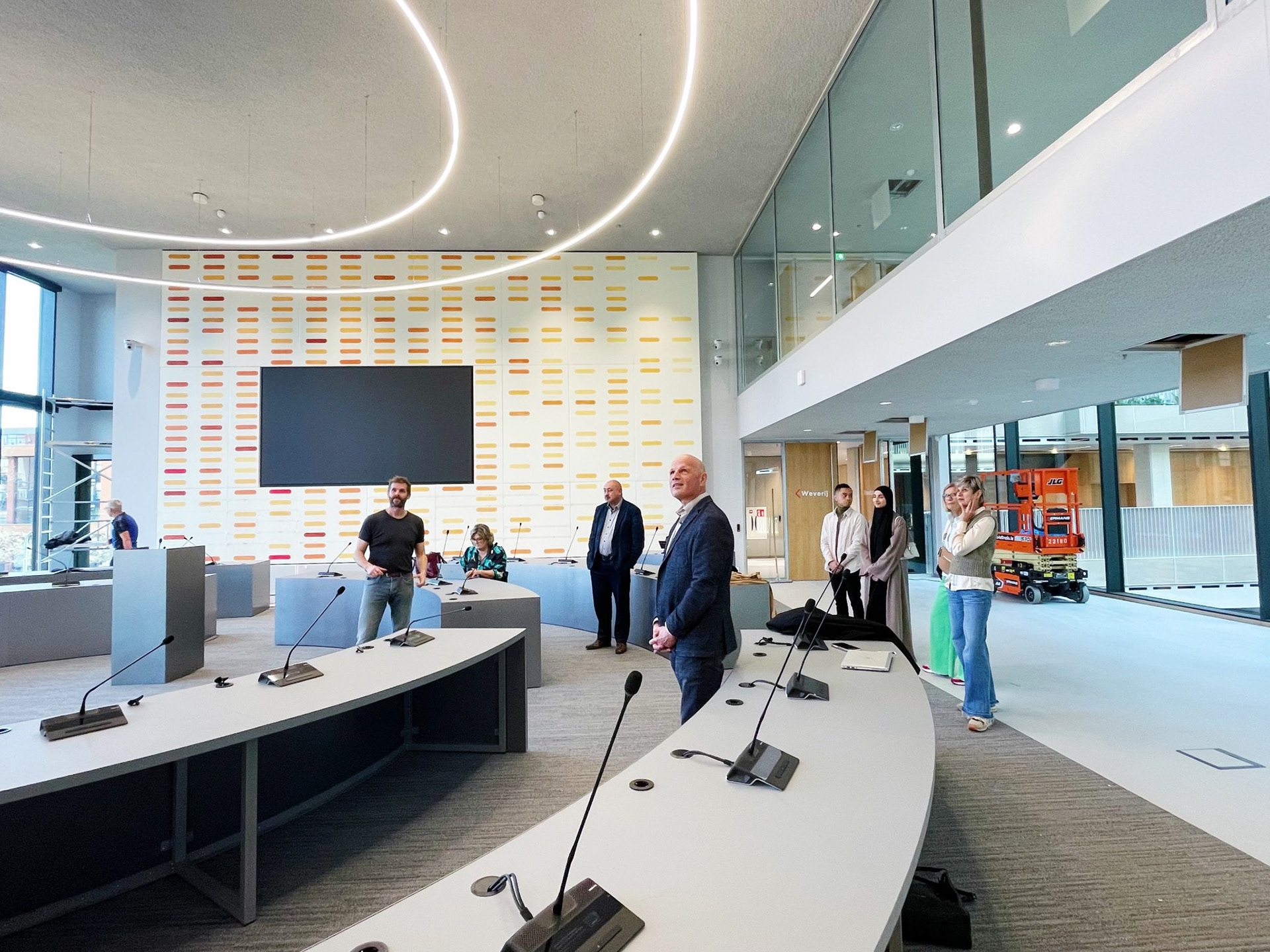 Kunstenaar Maurice van Venrooij voor zijn muurschildering in de raadzaal van het Huis voor de Stad in Helmond, wordt bezocht door wethouder Harrie van Dijk, enkele raadsleden en Julienne Tullemans, directeur van de expo Cacaofabriek.