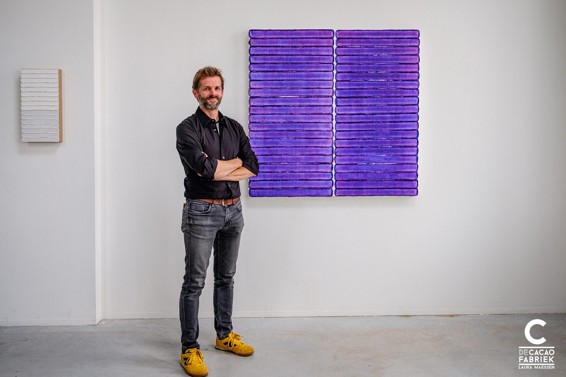 Kunstenaar Maurice van Venrooij voor twee van zijn schilderijen in de Cacaofabriek in Helmond