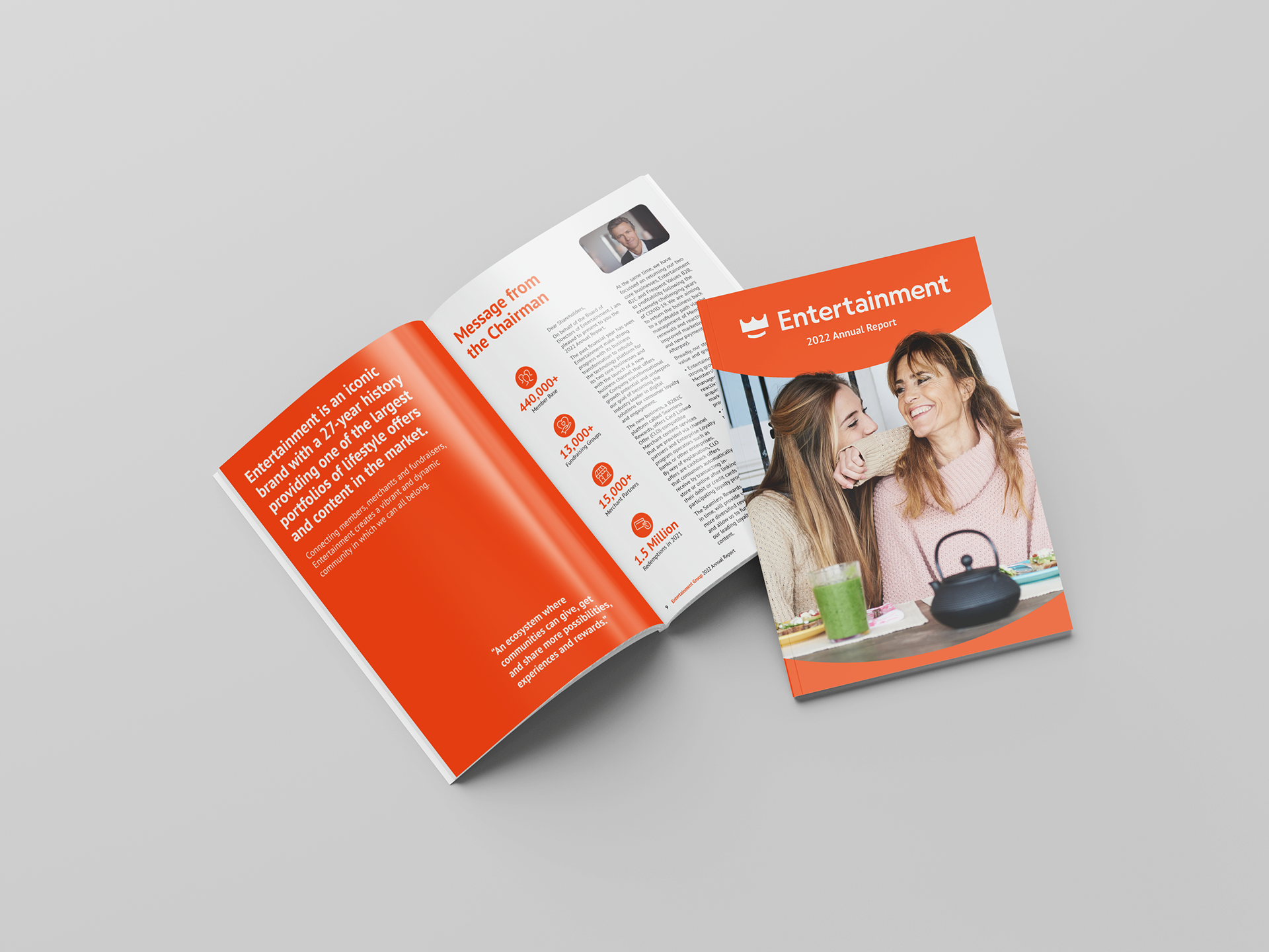 A mockup of an open and closed 'Entertainment 2022 Annual Report' brochure. The cover features a cheerful image of two women enjoying a meal together, with the title prominently displayed. The open pages highlight a message from the Chairman, along with key statistics about the brand's achievements, including member numbers and fundraising efforts. The design uses a bold orange theme with white text, emphasising the brand's 27-year history and its extensive offering of deals and content.