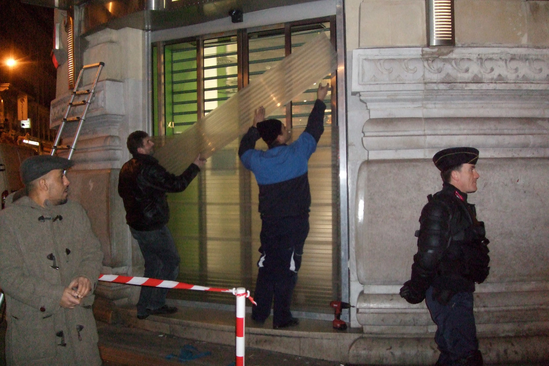 Preparing for New Year's Eve on the Champs Elysees: shops barricading their windows as if preparing for a hurricane. Soldier stands guard