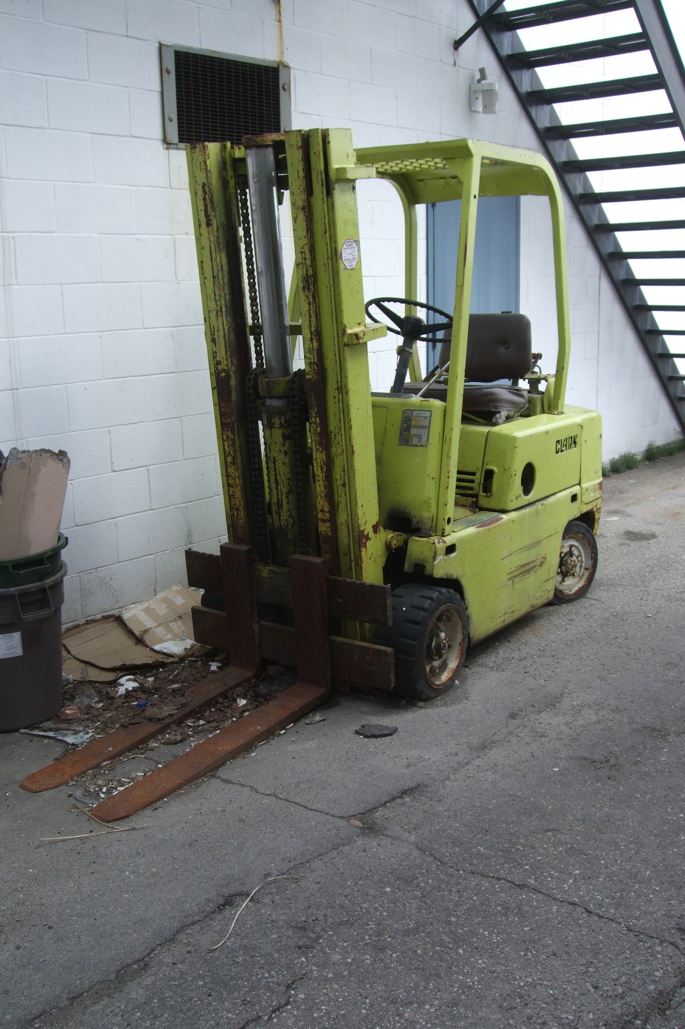 The brightly coloured forklift slowly rots away