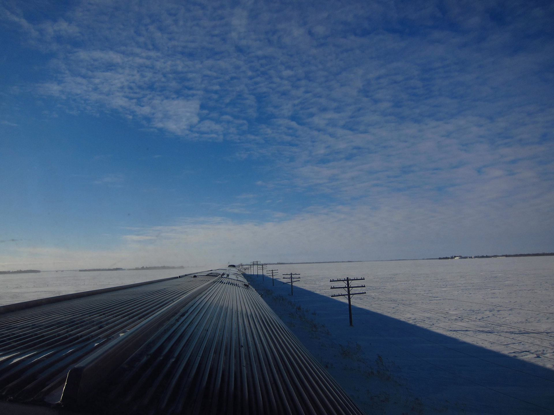 Stainless steel train, blue sky, white snow. The rail signal lines aren't used anymore, but it's cheaper to just leave them in place