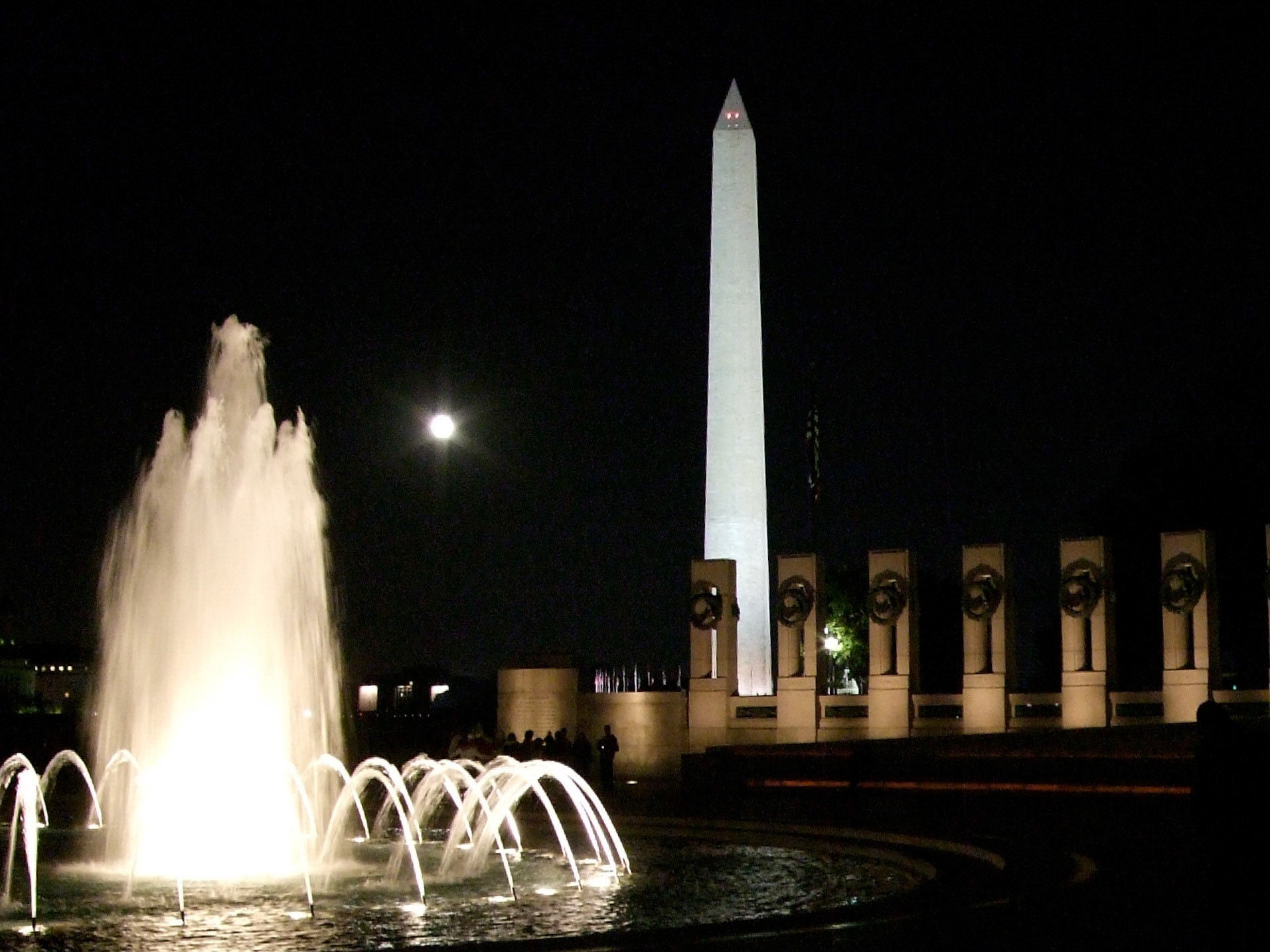 The full moon rose between the fountains of the World War II memorial and the Washington Monument