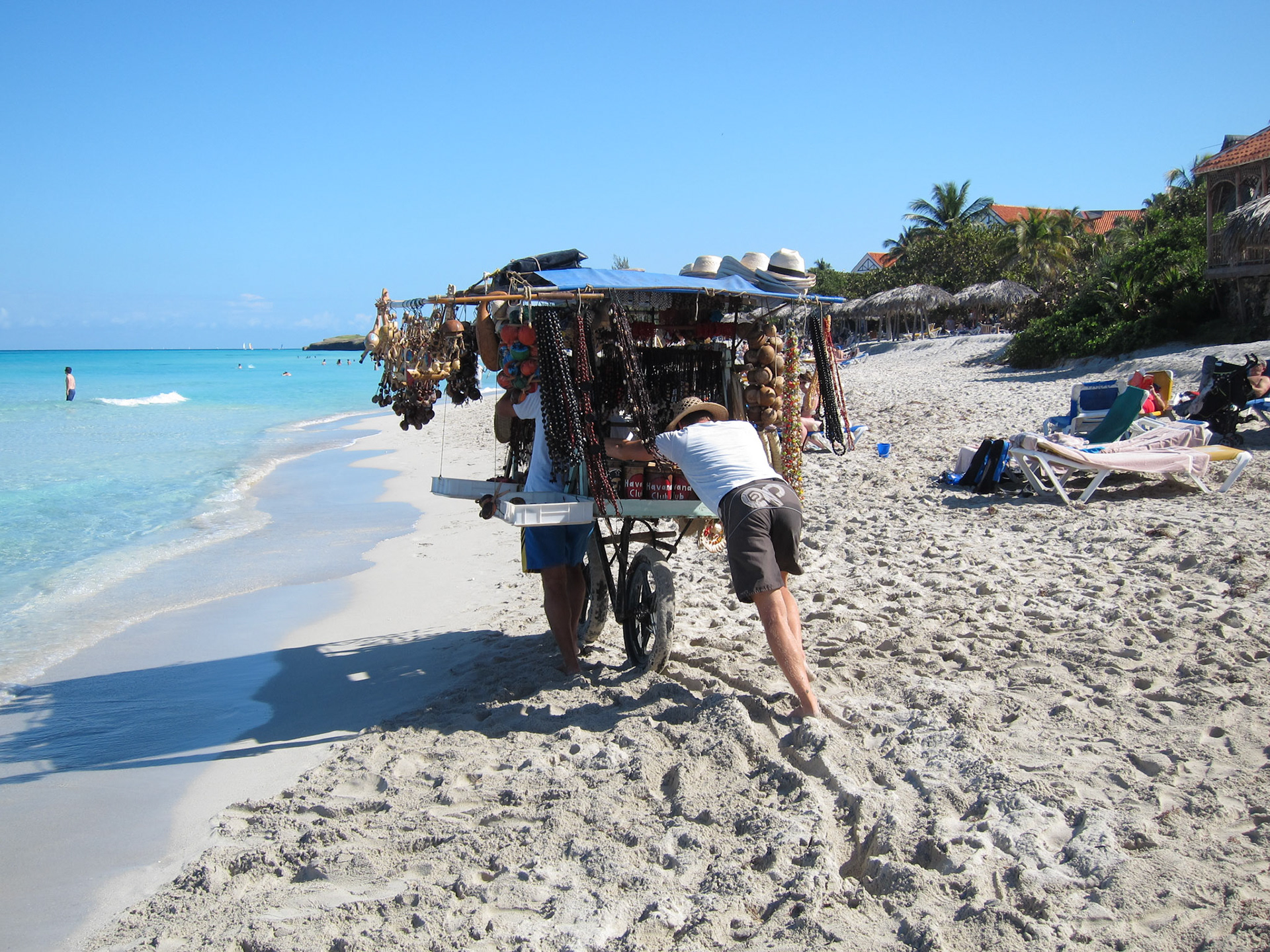A beach vendor struggling to move his massive cart