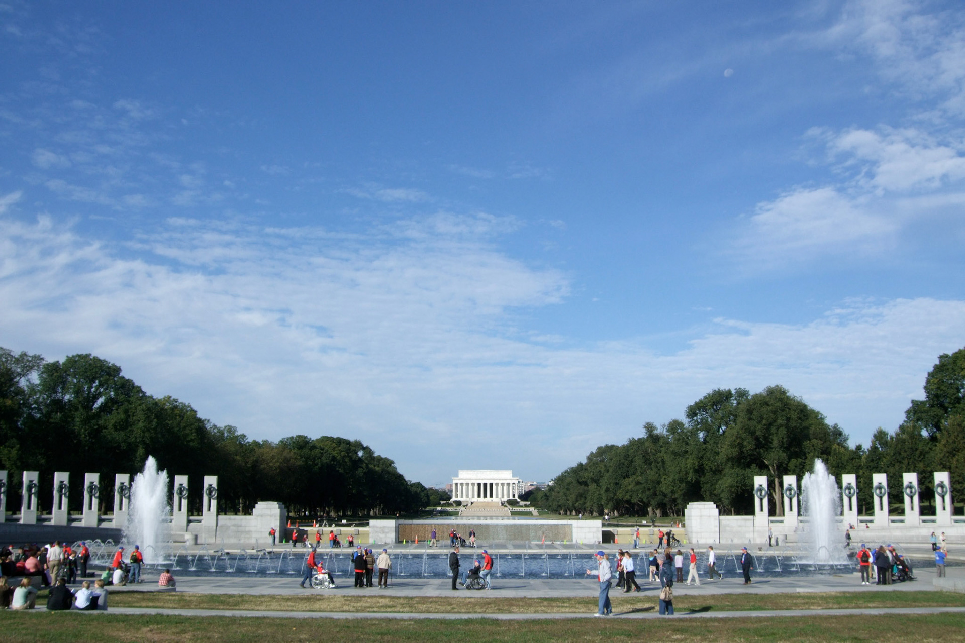 The beautiful World War II memorial by day, looking to the reflecting pool behind and the Lincoln Memorial in the distance. Veterans in red shirts
