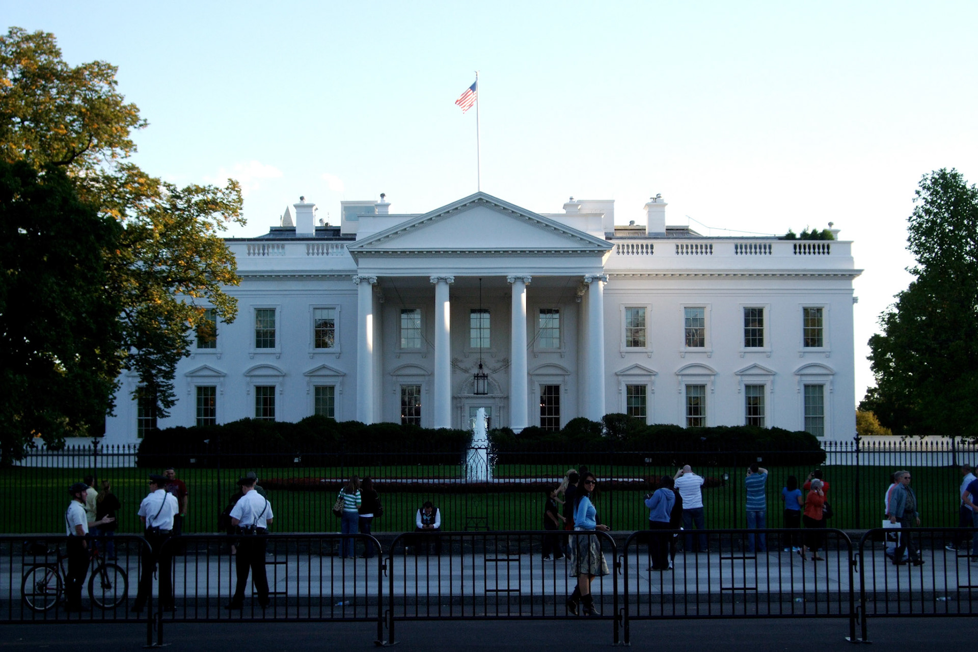 Small crowd, some secret service and barracades in front of the White House