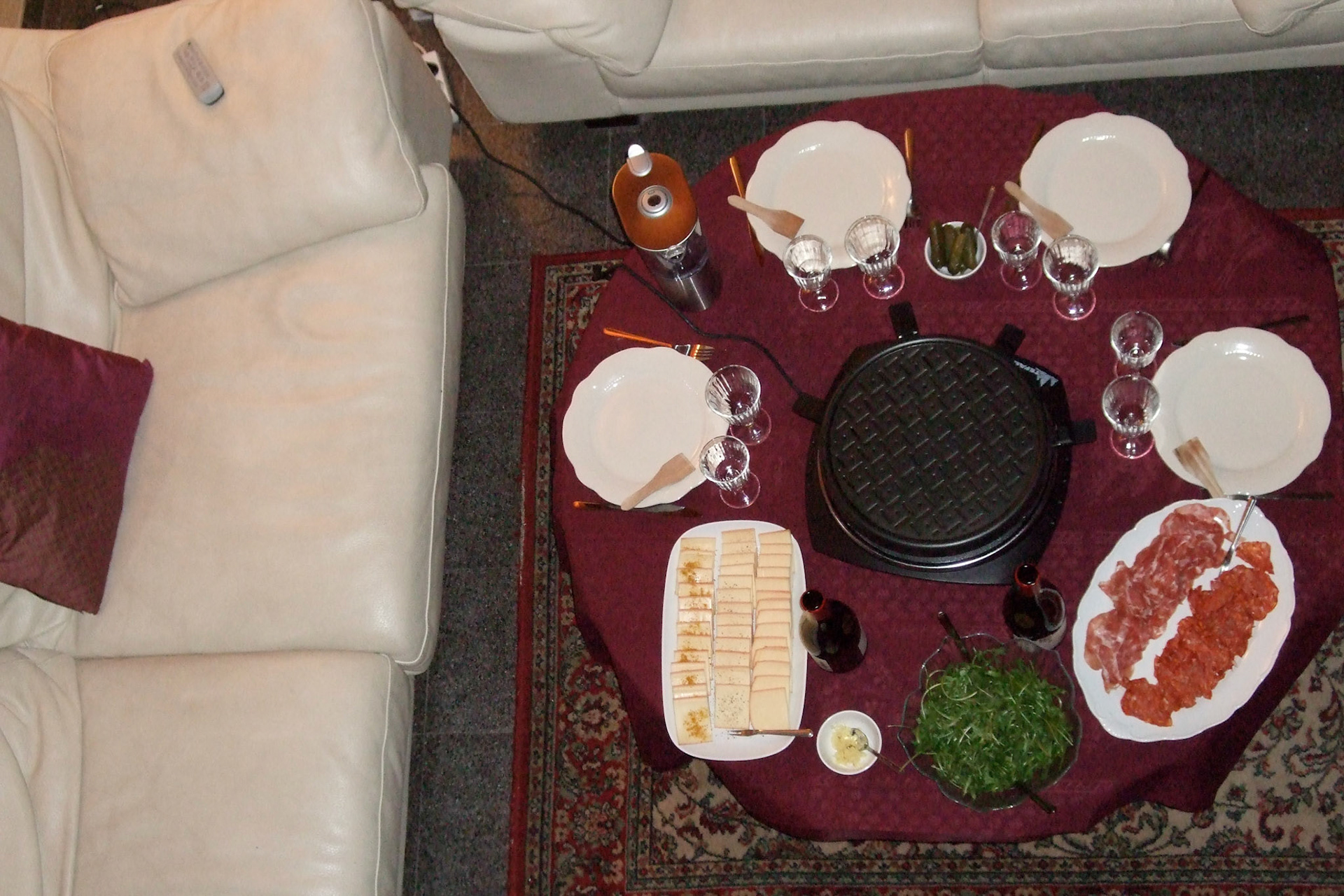 Meat, cheese (raclette), potatoes and wine with the raclette grill in the centre.