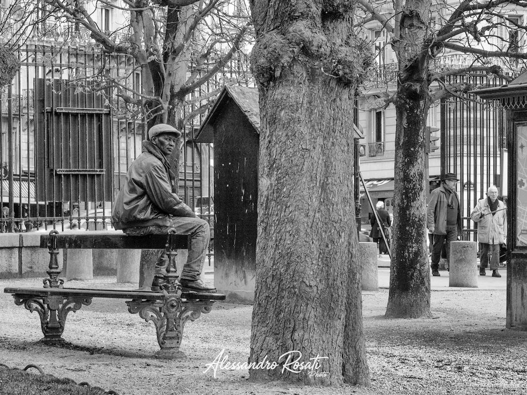 uomo seduto su panchina al parco di parigi