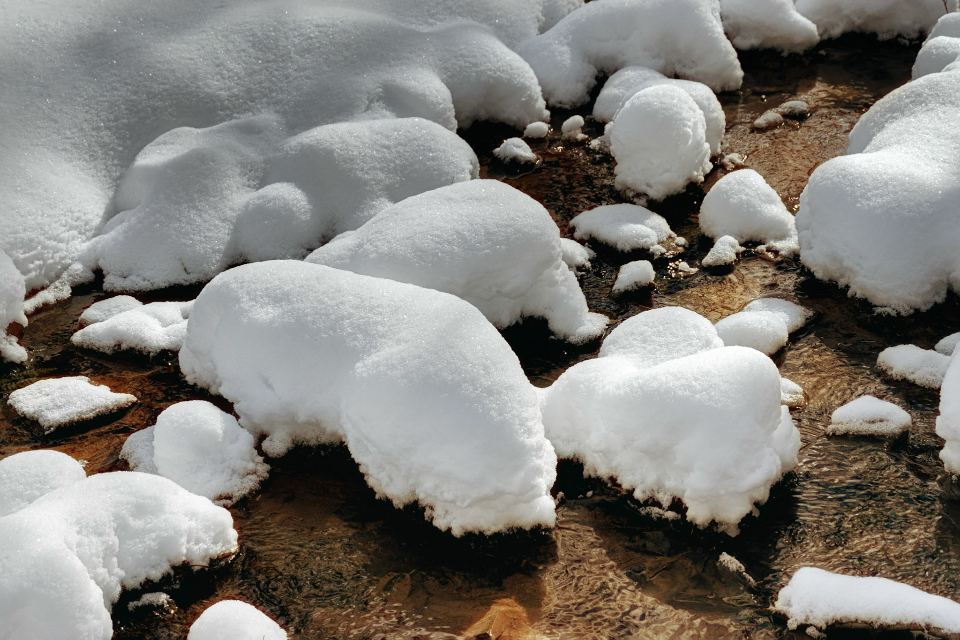 Heavy Snow Falls on Rocks in Small Creek