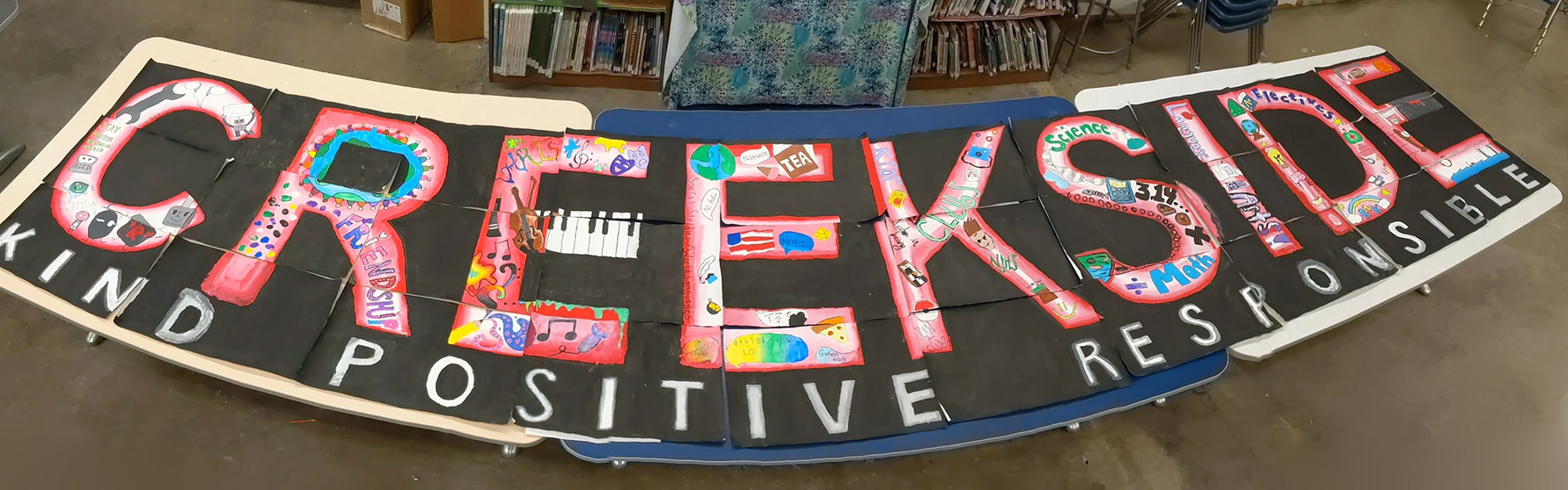 The advanced drawing and painting class created their own custom design to make a 10-foot (3 meter) long mural. Each letter represented a different facet of our school community.