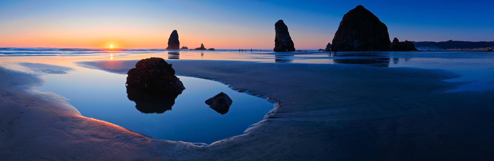 This Panorama image of Cannon Beach at sunset was made during a new moon evening where the low tide was especially low and created little ponds at places which would be covered by water during a regular low tide. Cannon Beach is on the Oregon Pacific coast.