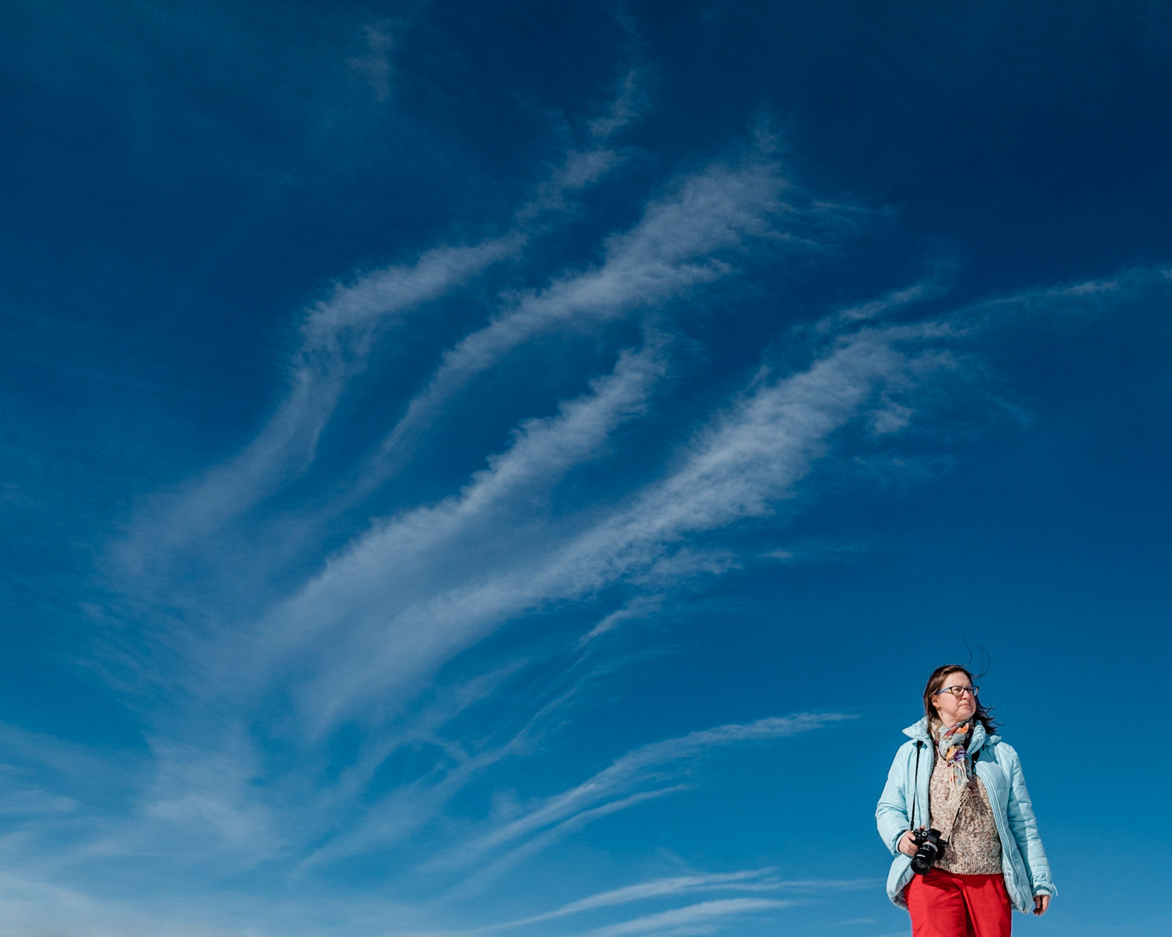 Olena with a camera in her hands and clouds in the background.