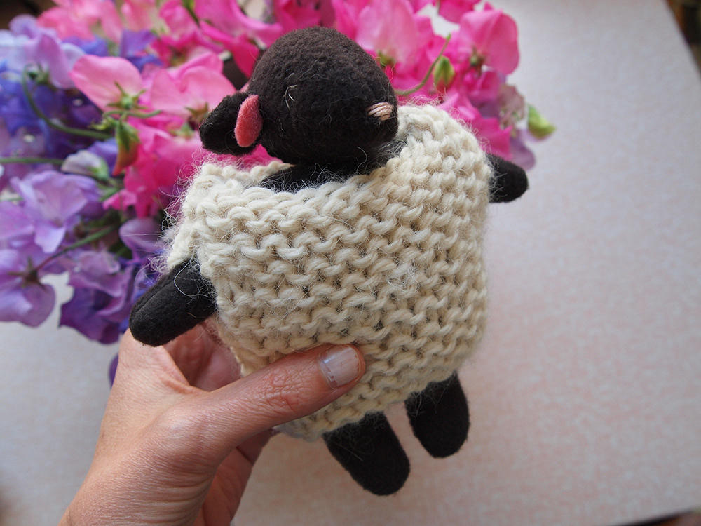 Sewn black sheep with a knitted white vest/sheepskin
