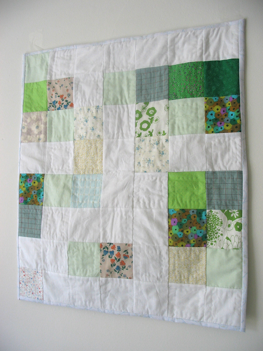 Patchwork quilt for a baby in greens and white