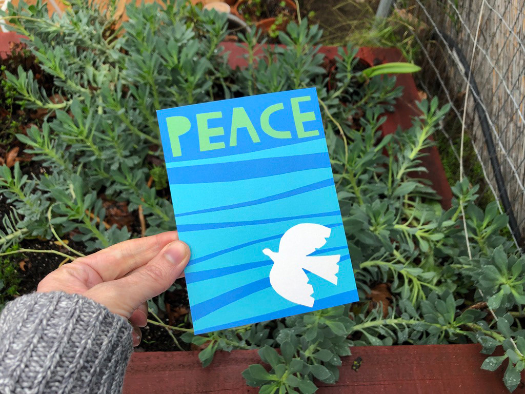 Illustrated with cutout shapes card that says Peace and has a dove on it