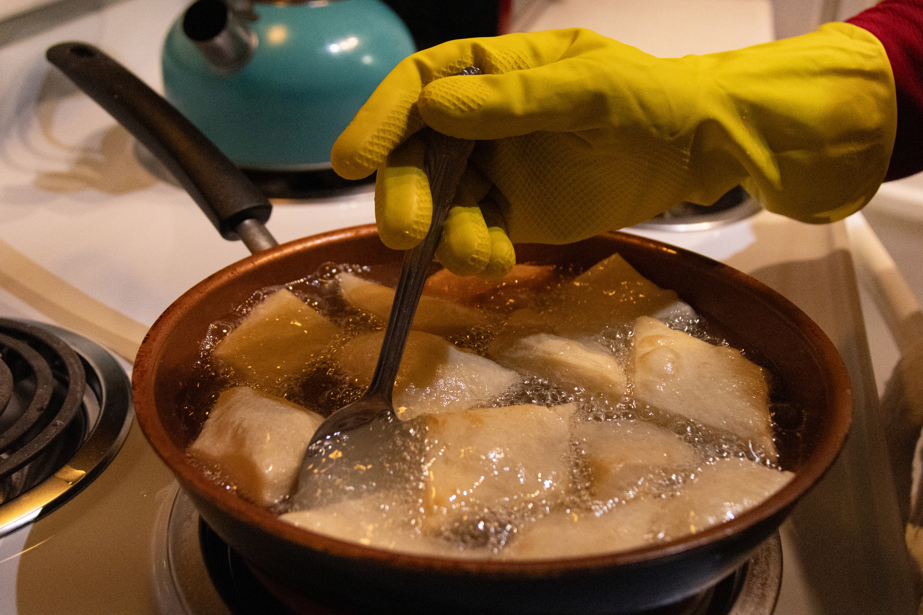 Aisha Ibrahim fries Sudanese fatira in oil on Saturday, Feb. 23, 2025, in Lincoln, Neb. She has prepared several other Sudanese dishes for her guests, including ful. As the guests arrive, they bring more food or bottles of water to contribute to the group. 