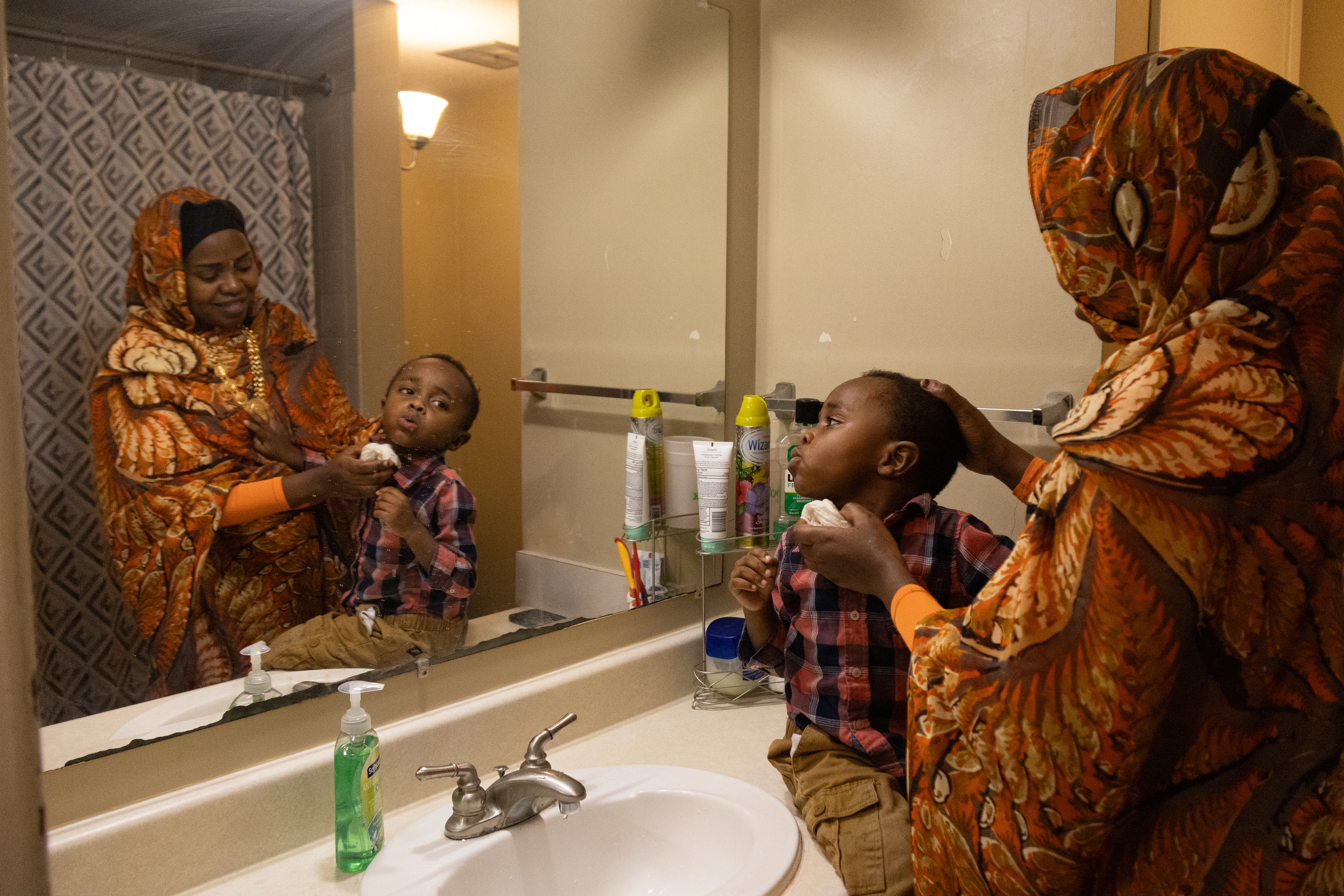Aisha Ibrahim washes her son Bugala Abdul’s face as she gets her children ready for bed on Saturday, Feb. 23, 2025, in Lincoln, Neb. After the sister get-together, Ibrahim helps her children brush their teeth and then settles them down with a story. 