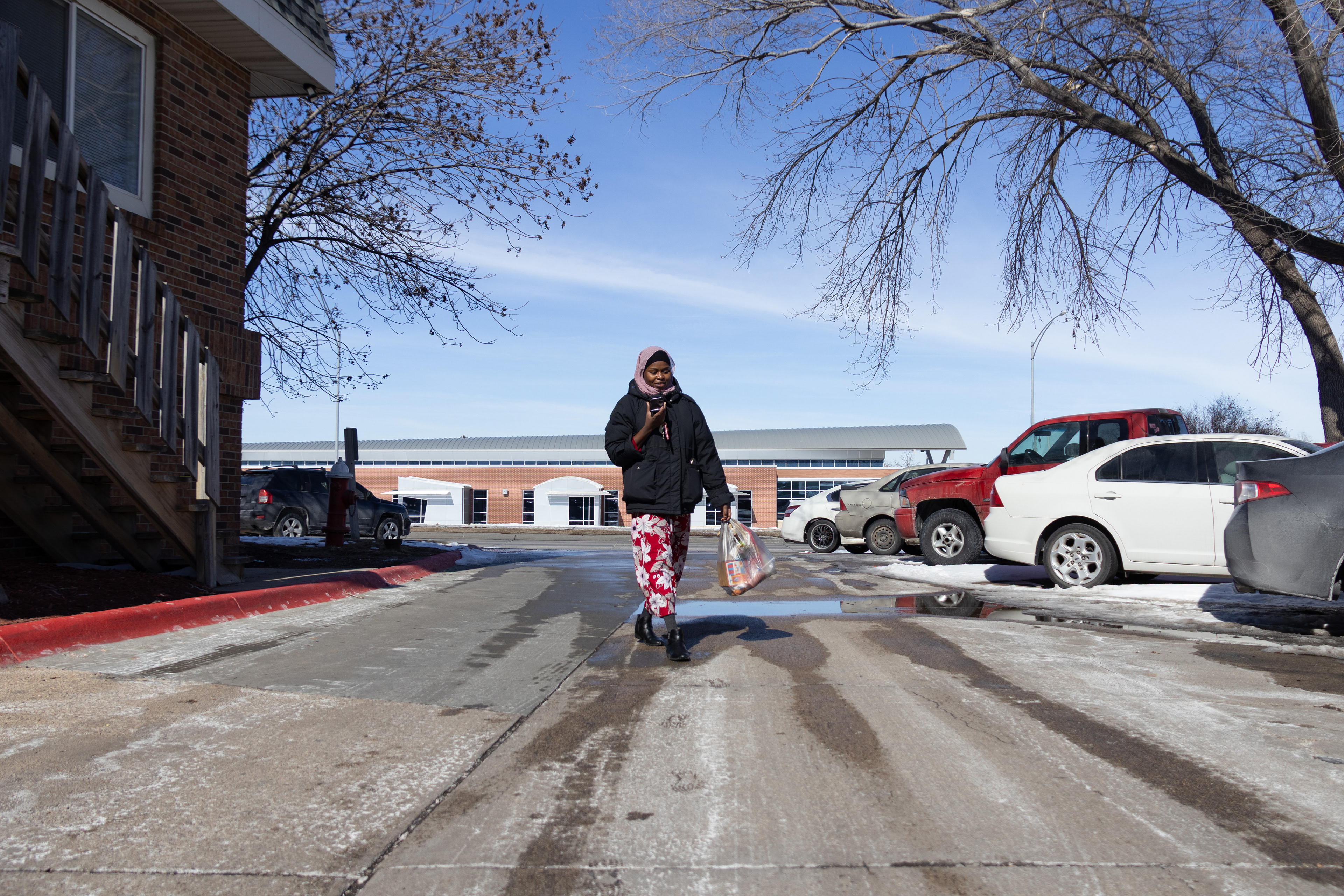 Aisha Ibrahim leaves her apartment building to go to the grocery store on Saturday, Feb. 23, 2025, in Lincoln, Neb. Ibrahim needs more vegetables and fruits for the dishes she will make for the guests that will visit in the evening. 