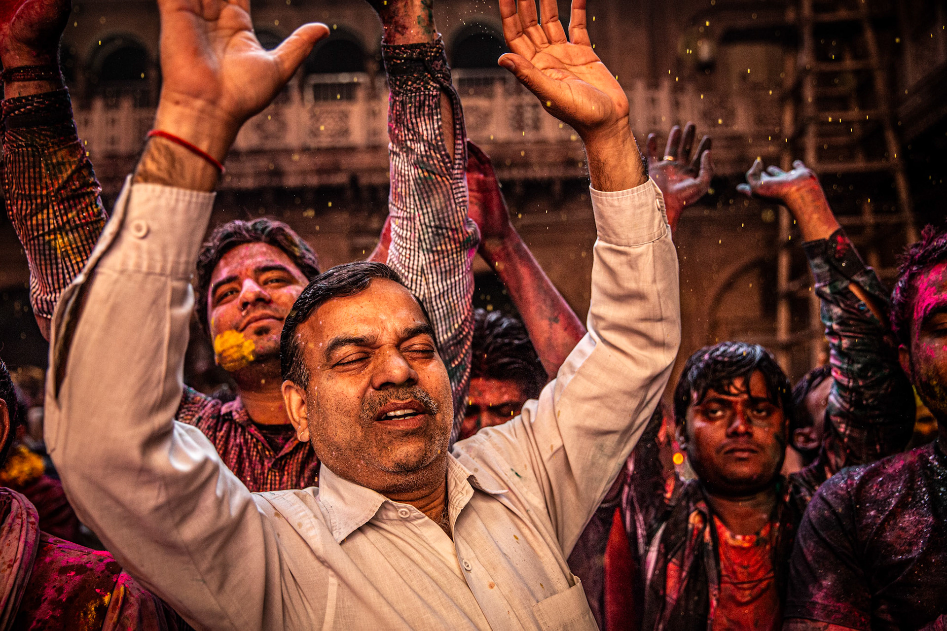 Man raising his arms in devotion during Holi celebrations inside Bankey Bihari temple. Vrindavan, India