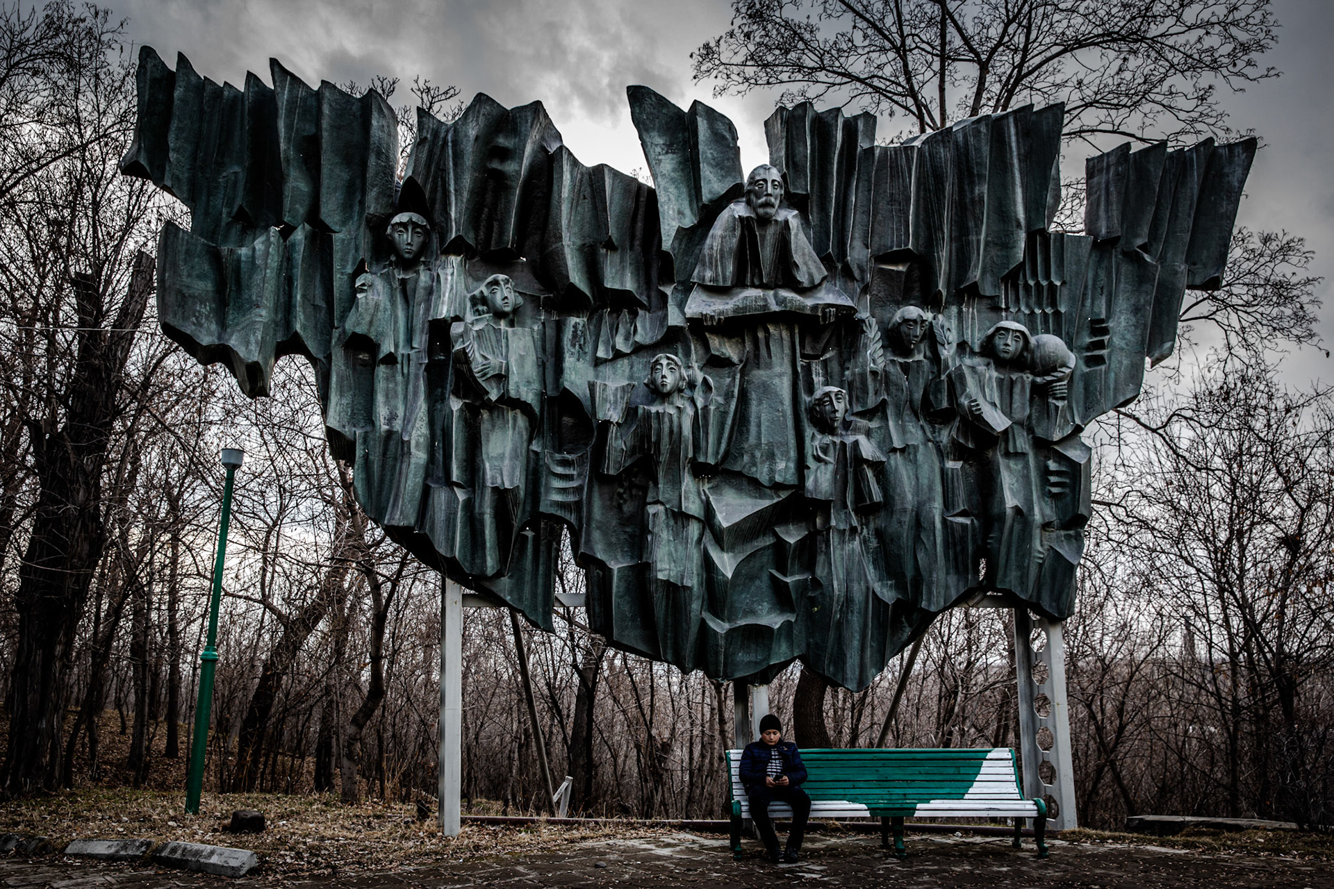 Soviet era sculpture above a boy sitting down at Gyumri Central Park. Armenia
