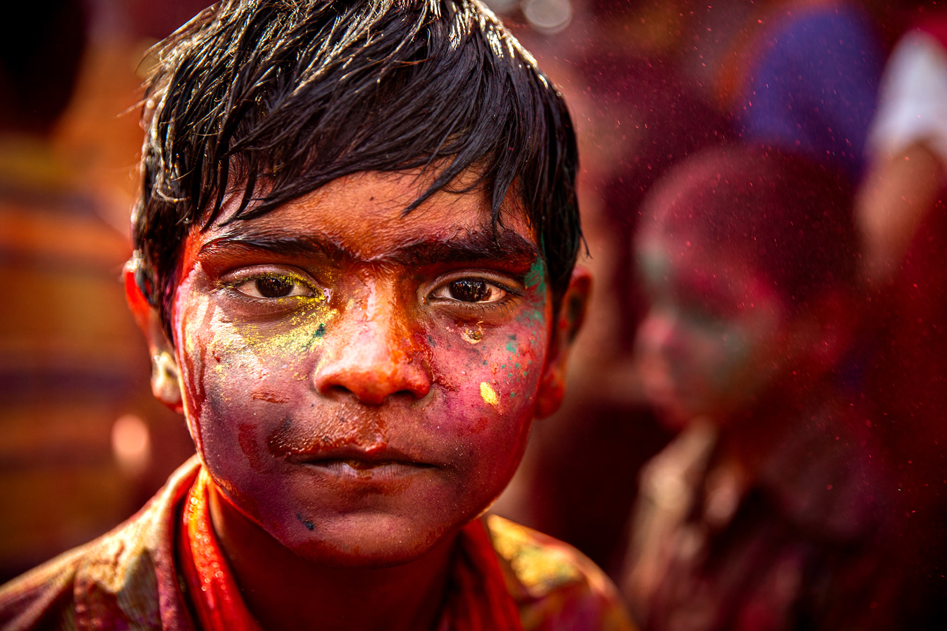 Boy covered with colored water and gulal during Holi. Mathura, India